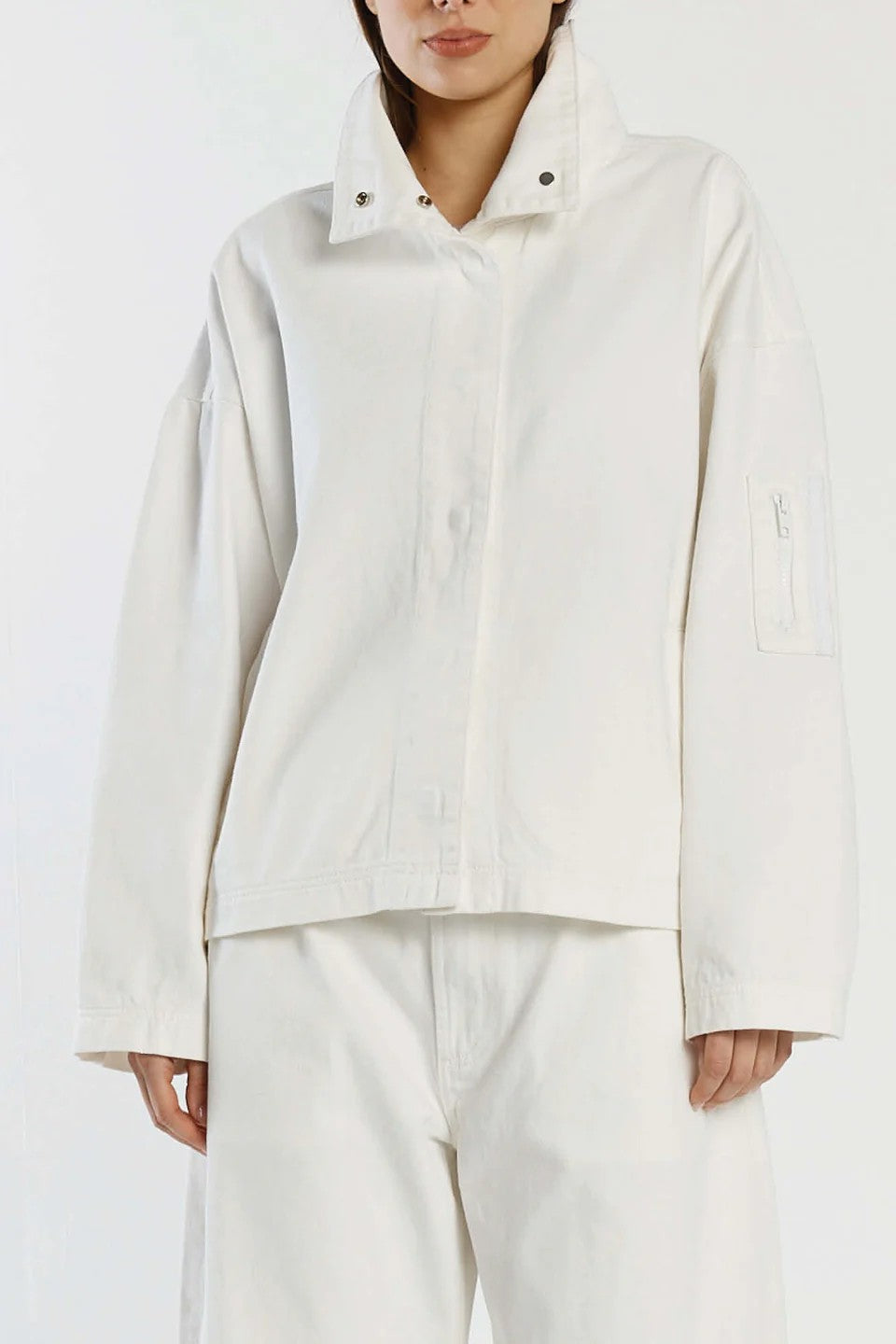 Person wearing a light-colored jacket and pants on a white background