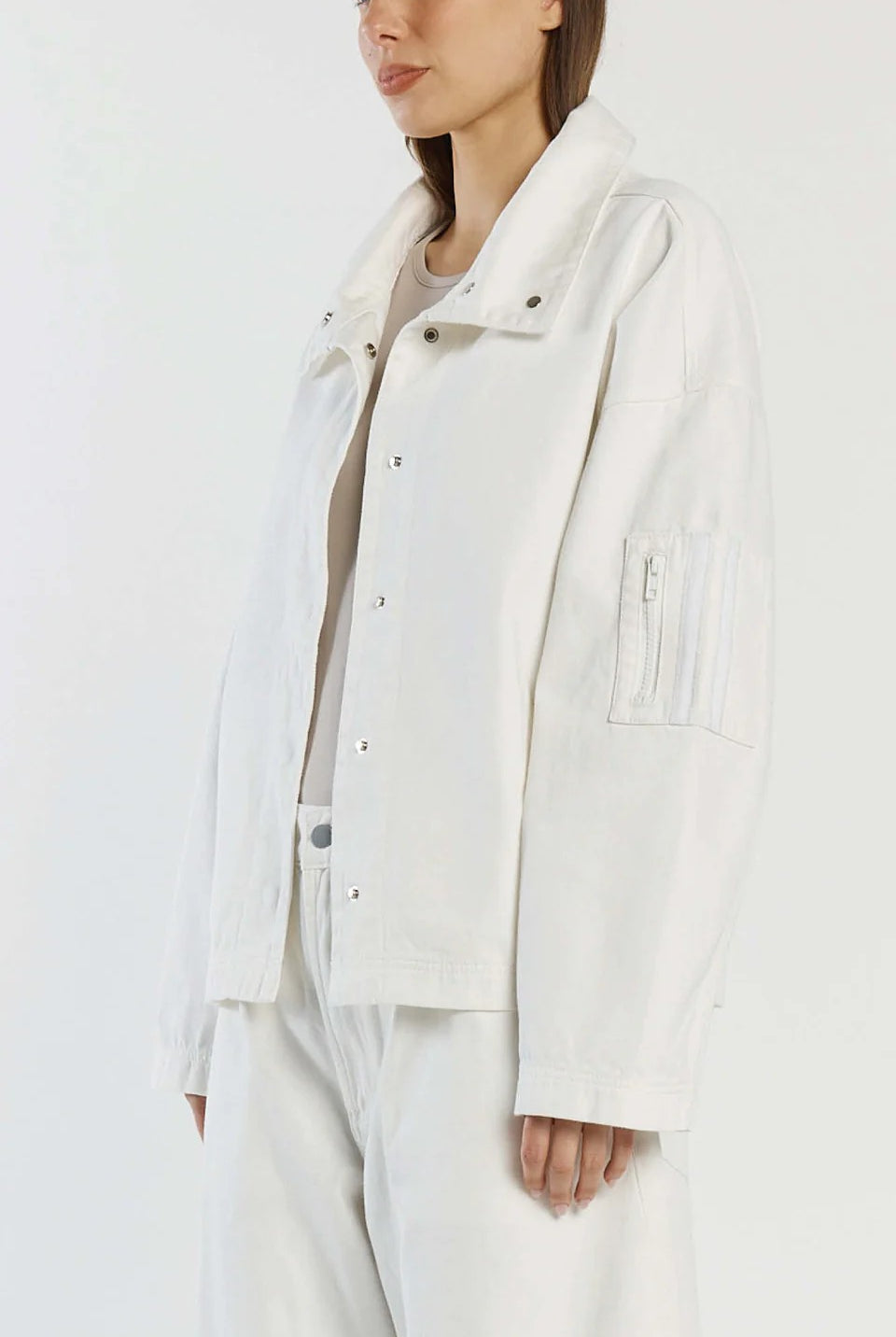 Person wearing a white jacket with a plain background