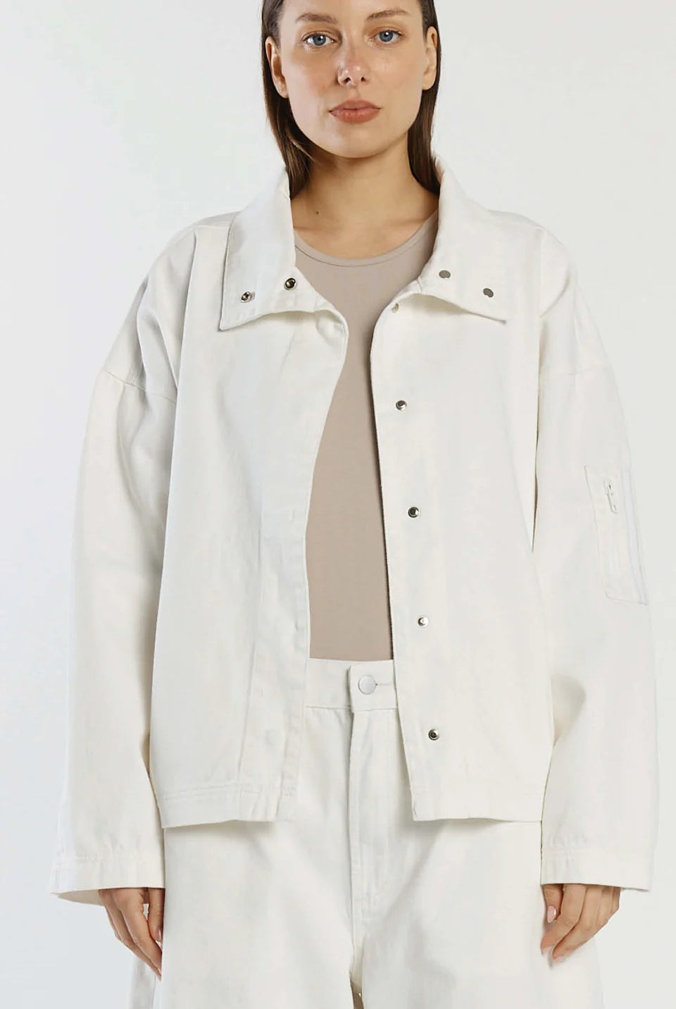 Woman wearing a white jacket and pants against a white background