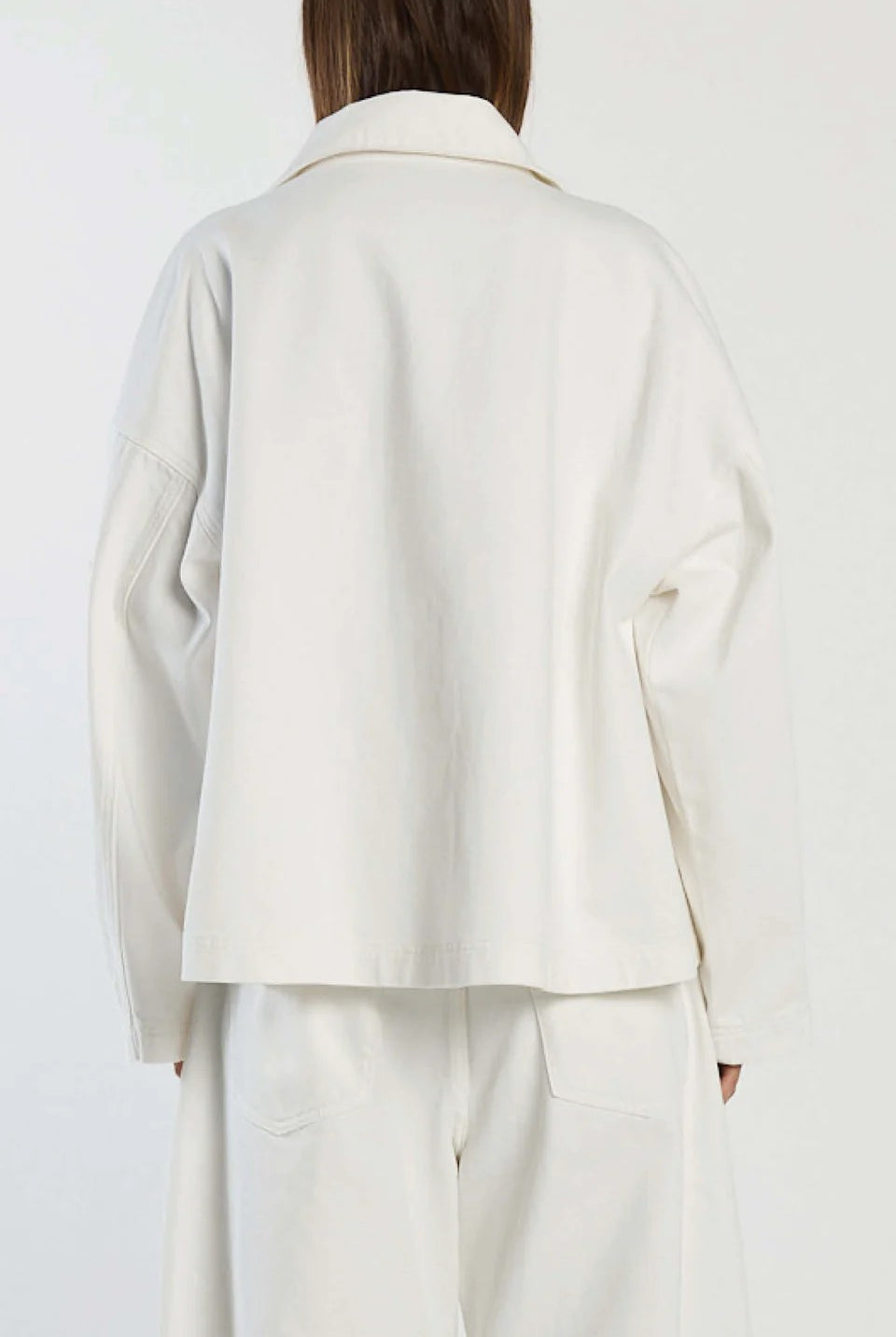 Person wearing a white coat and pants on a plain background back view