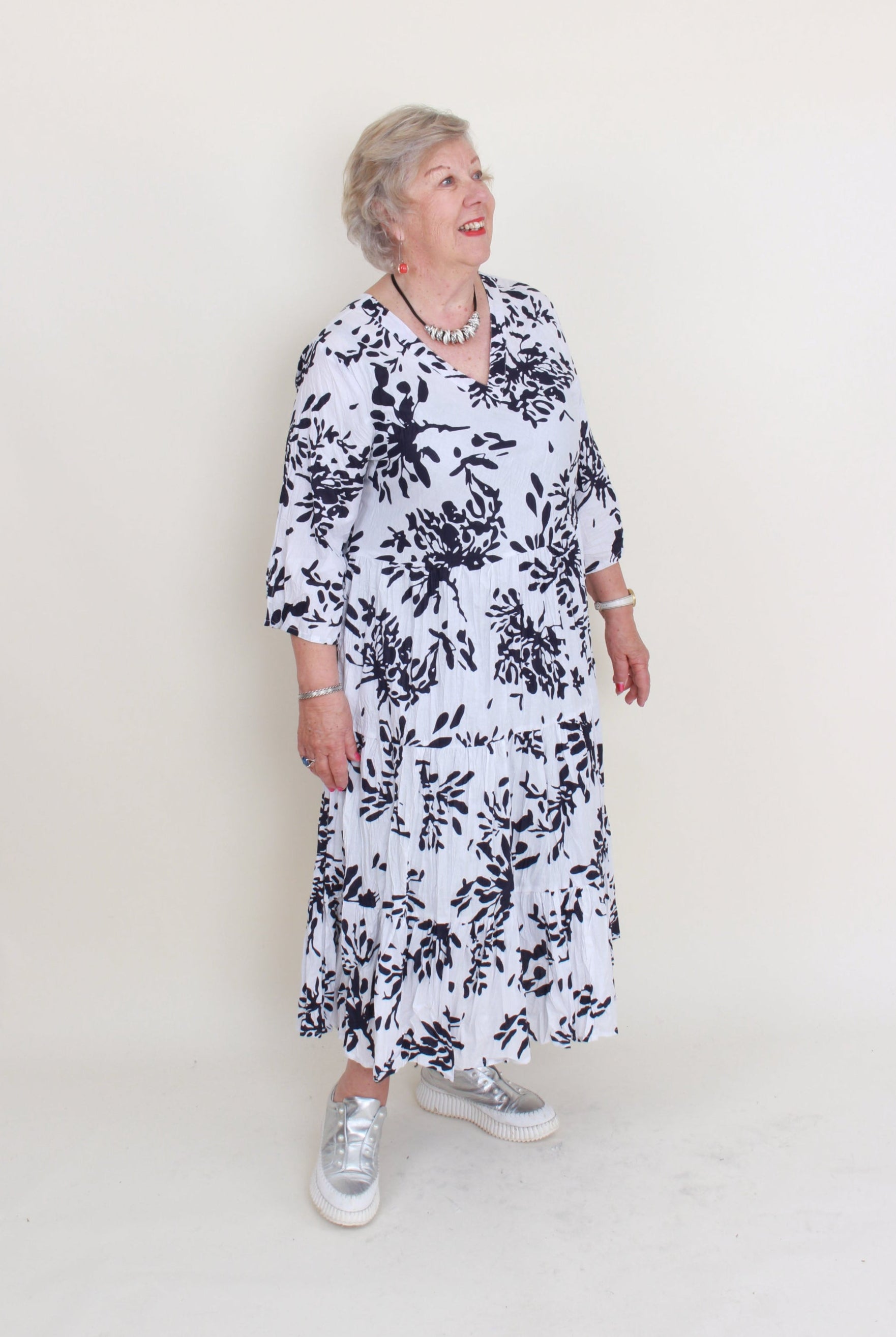 Person wearing a black and white floral dress on a plain background