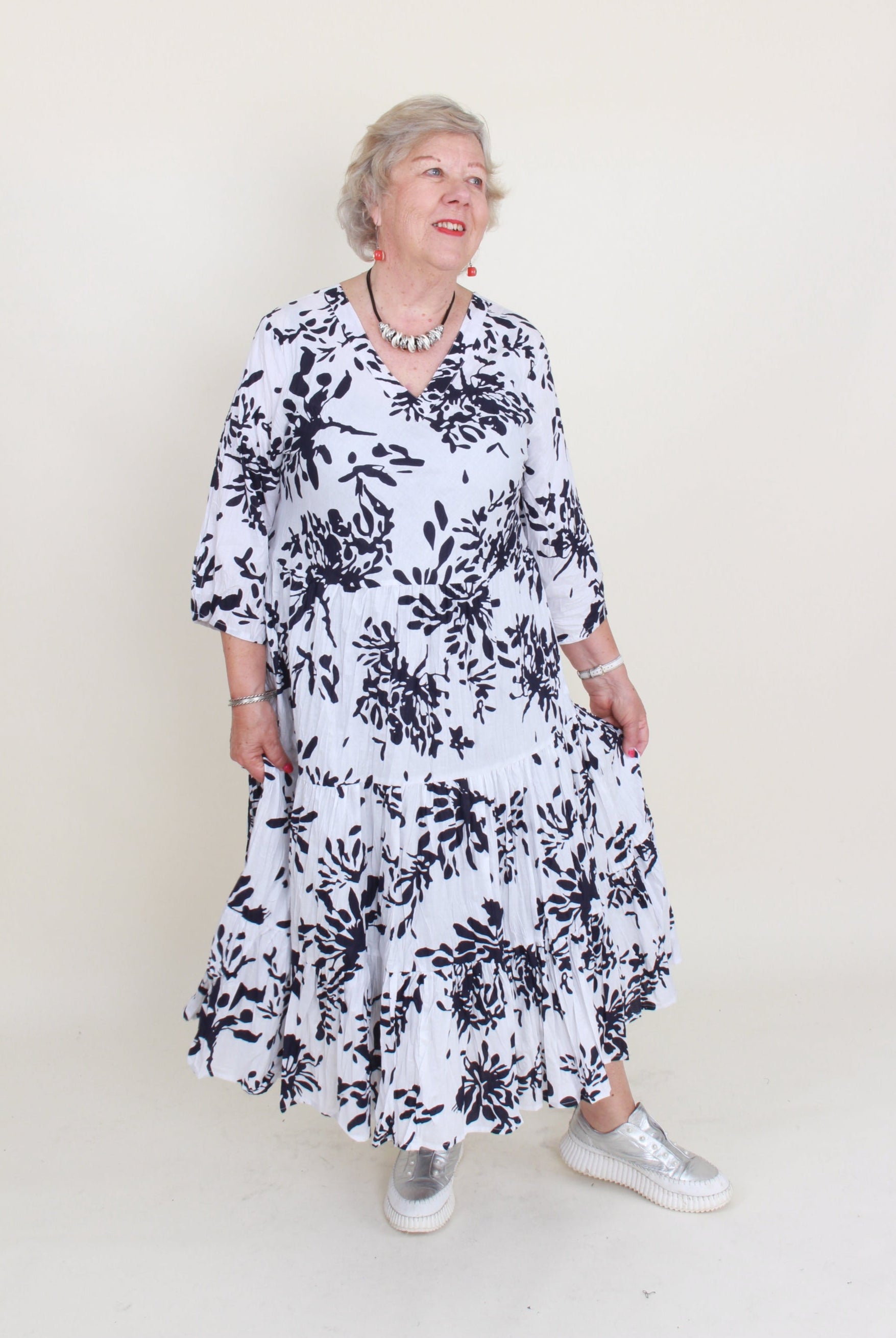 Person wearing a black and white floral dress on a plain background