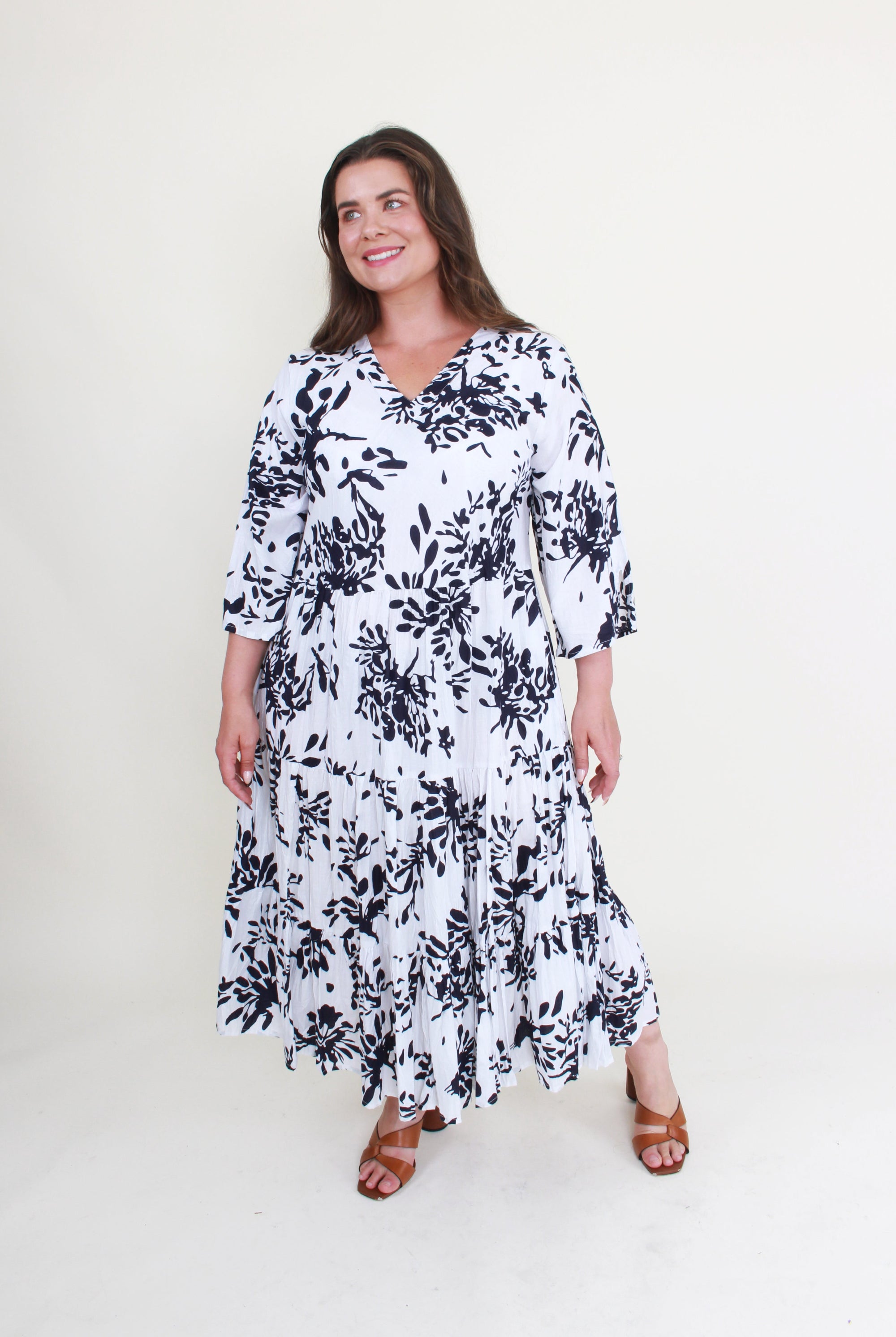 Woman wearing a white dress with black floral pattern on a white background
