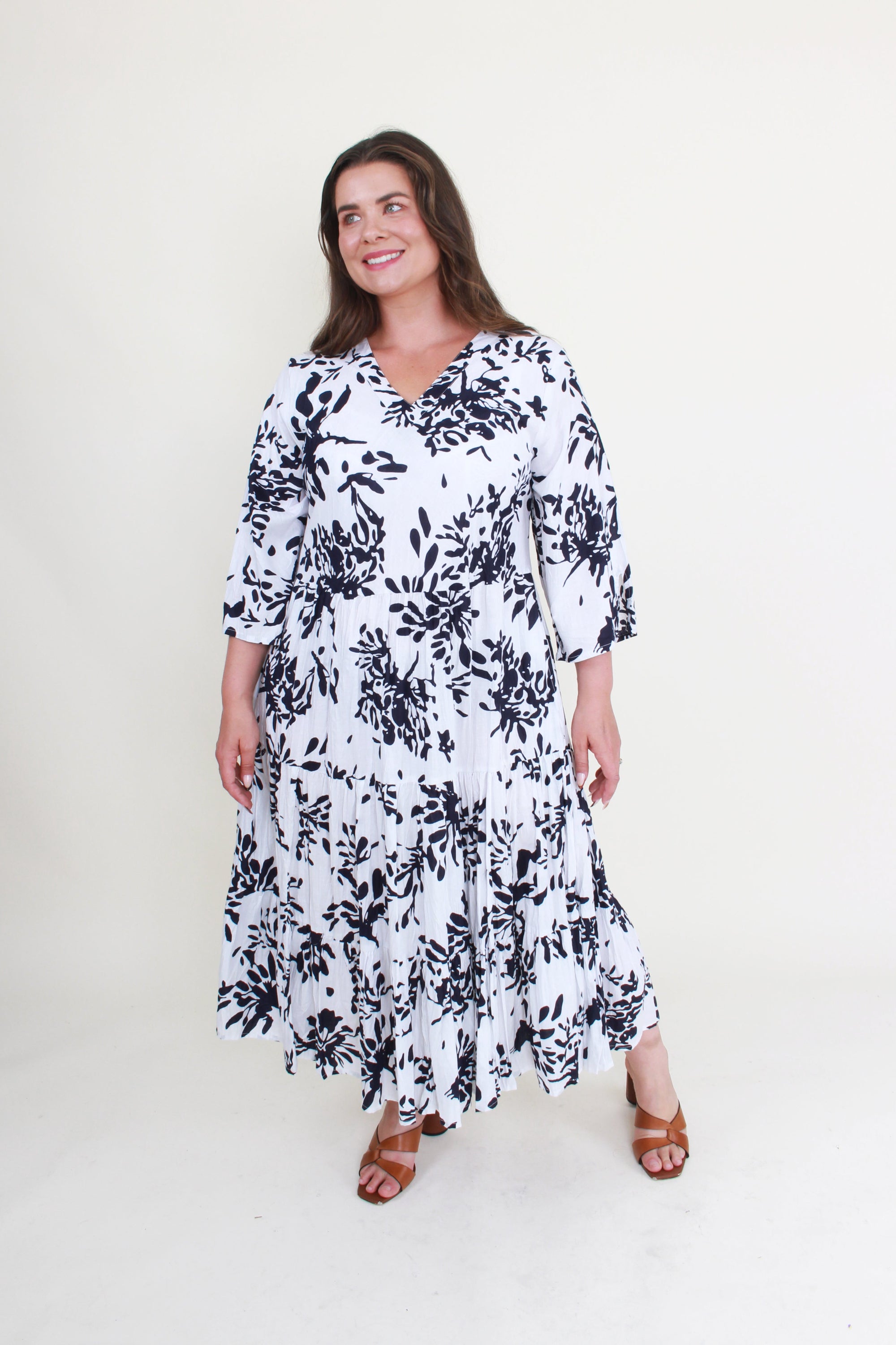 Woman wearing a white dress with black floral pattern on a white background