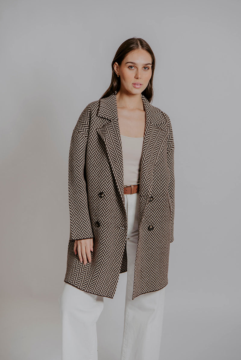 Woman wearing a patterned coat against a plain background