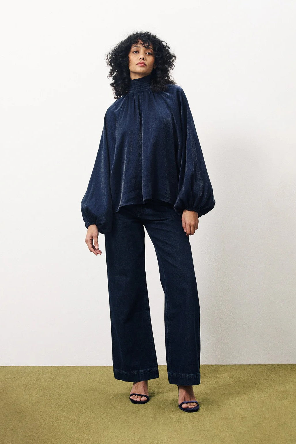 Person wearing a dark blue outfit with wide-leg pants on a plain background