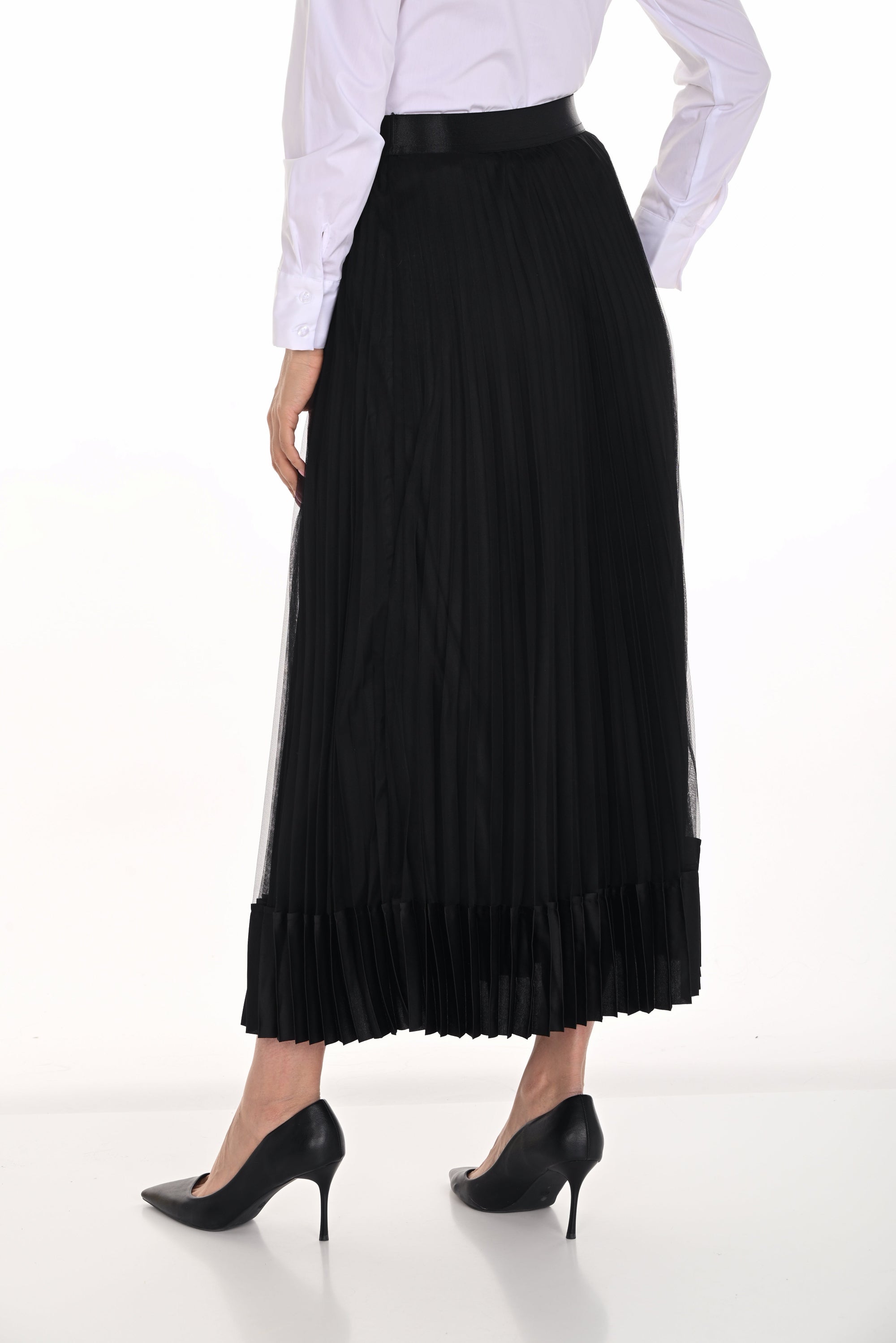 Person wearing a black pleated skirt and white blouse on a white background back angle