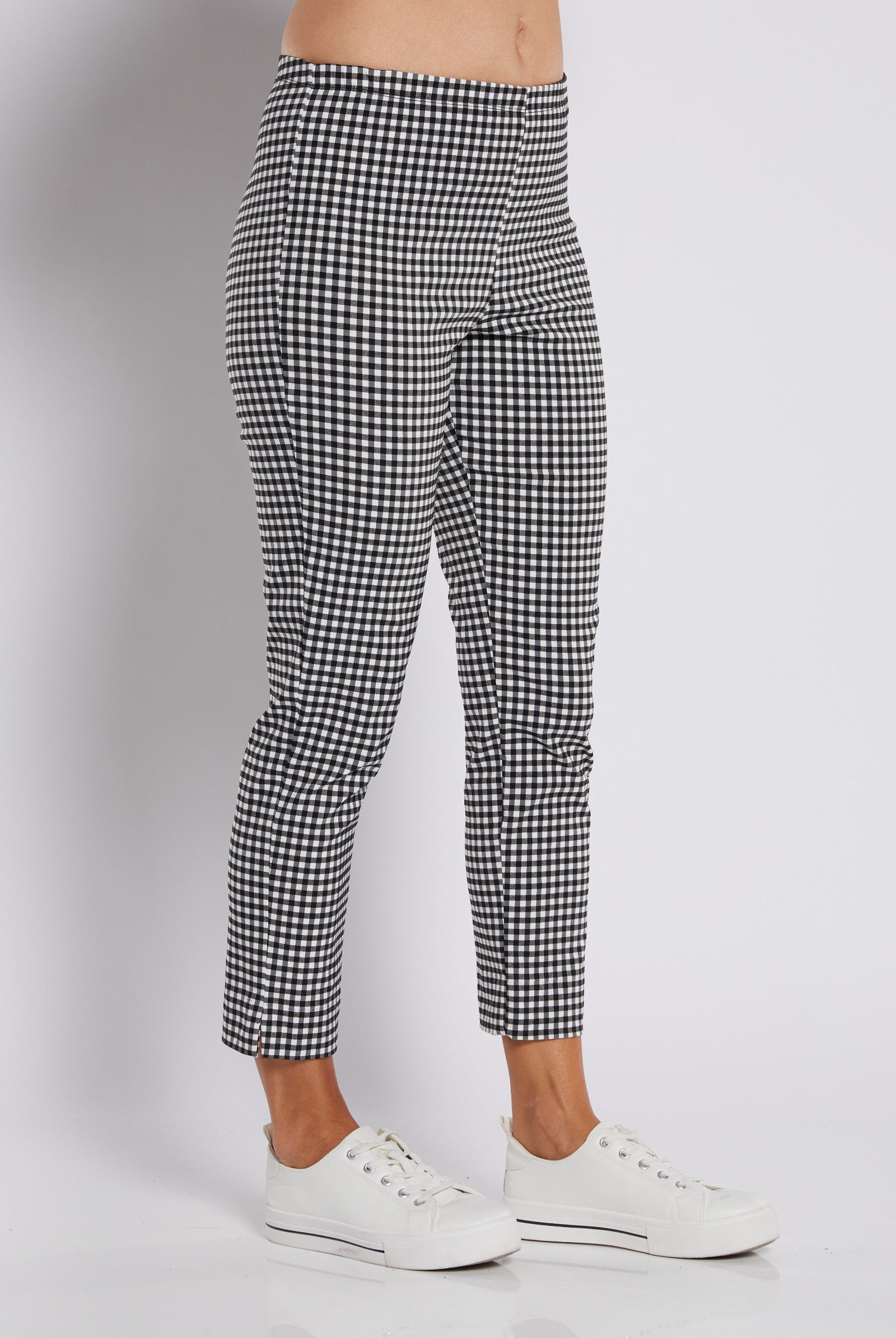 Black and white gingham patterned cropped pants worn by a model with white sneakers, shown from the waist down on a light gray studio background.