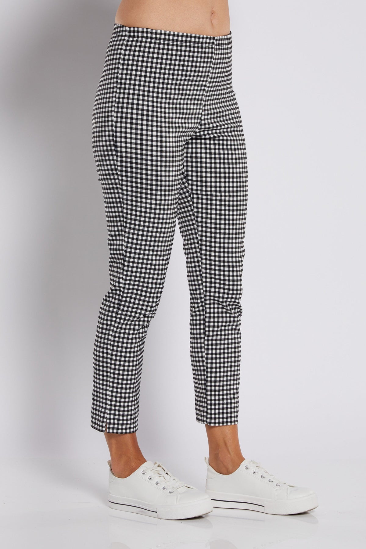 Black and white gingham patterned cropped pants worn by a model with white sneakers, shown from the waist down on a light gray studio background.