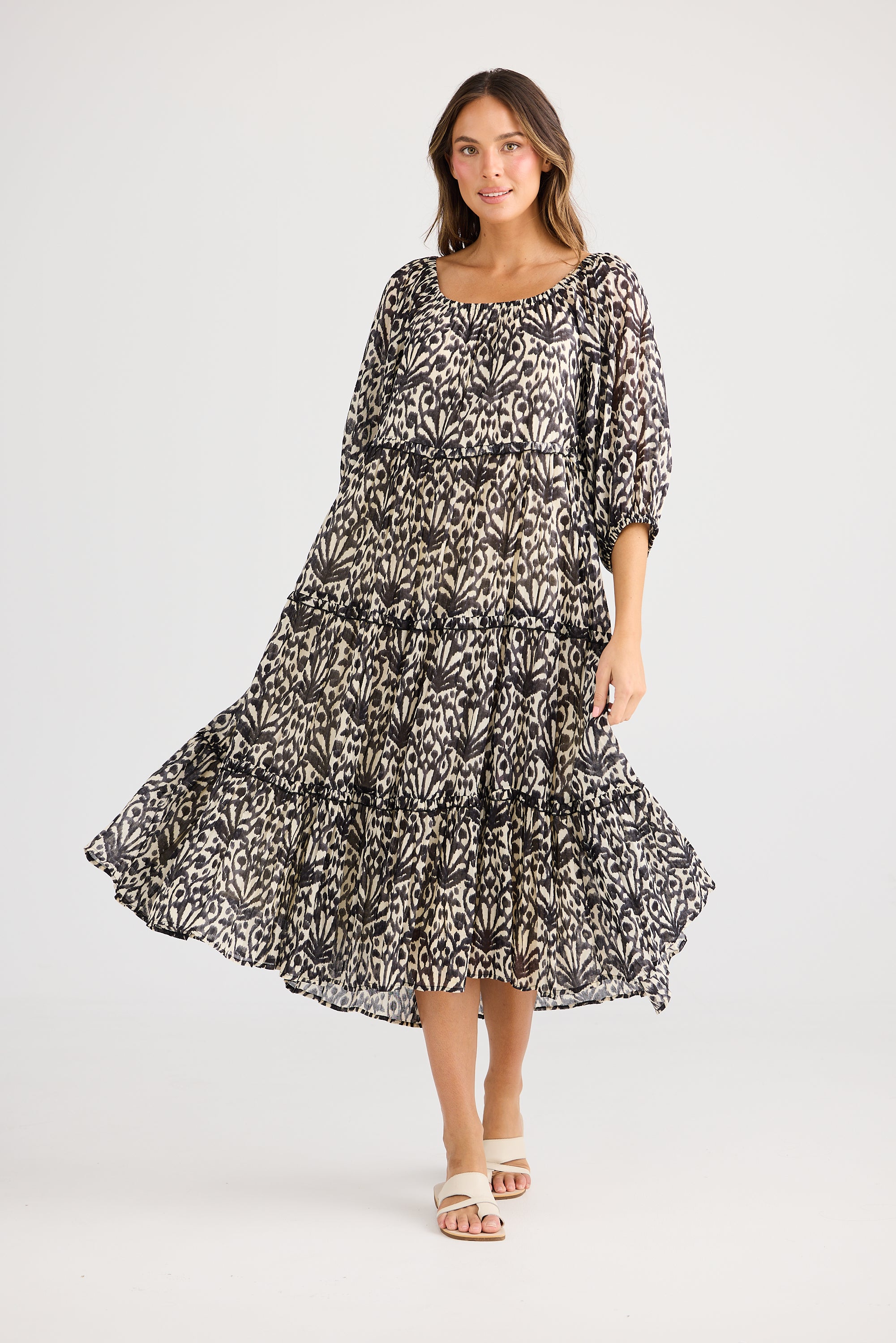 model wearing black cream long floral dress against white background