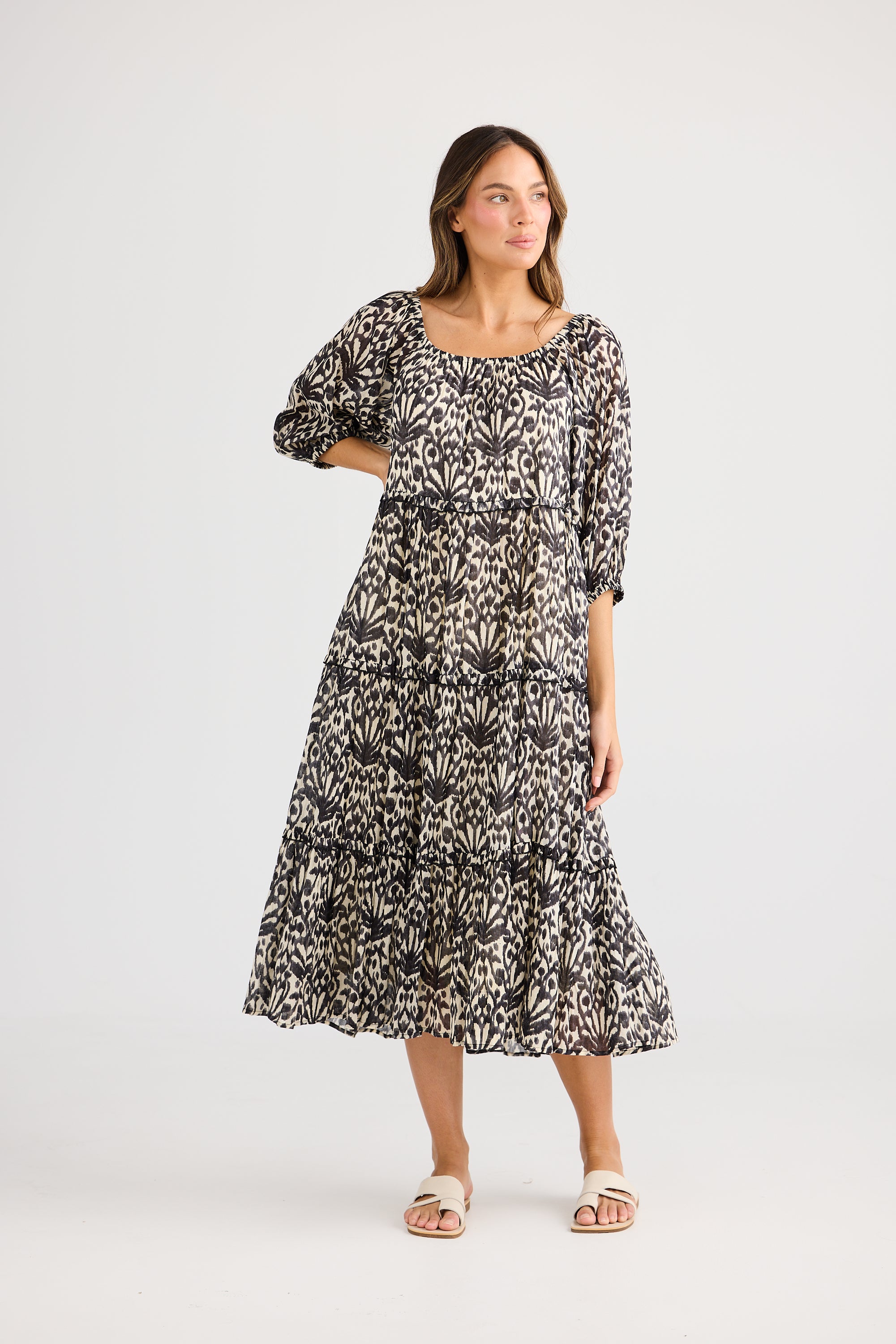 model wearing black cream long floral dress against white background