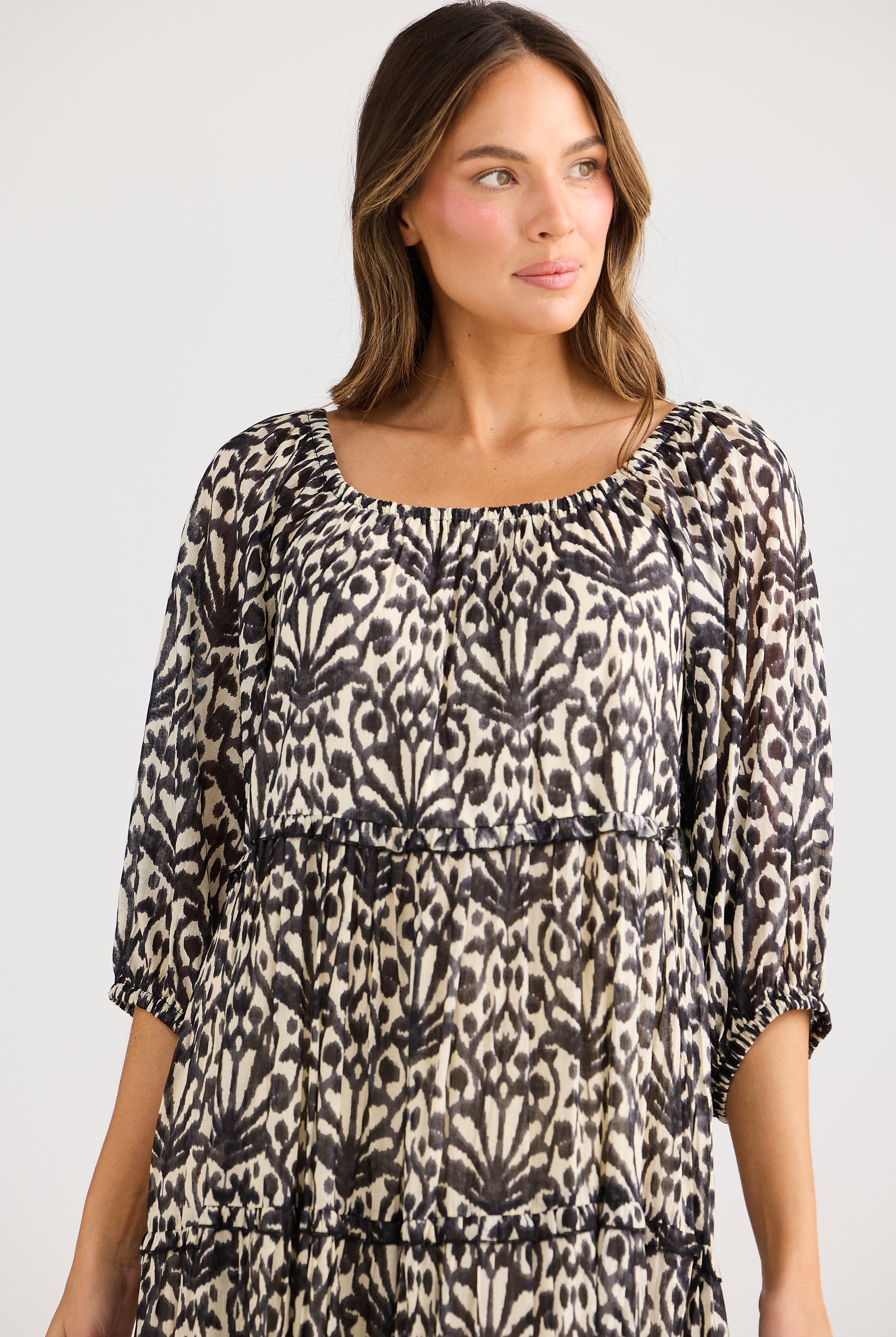 model wearing black cream long floral dress against white background