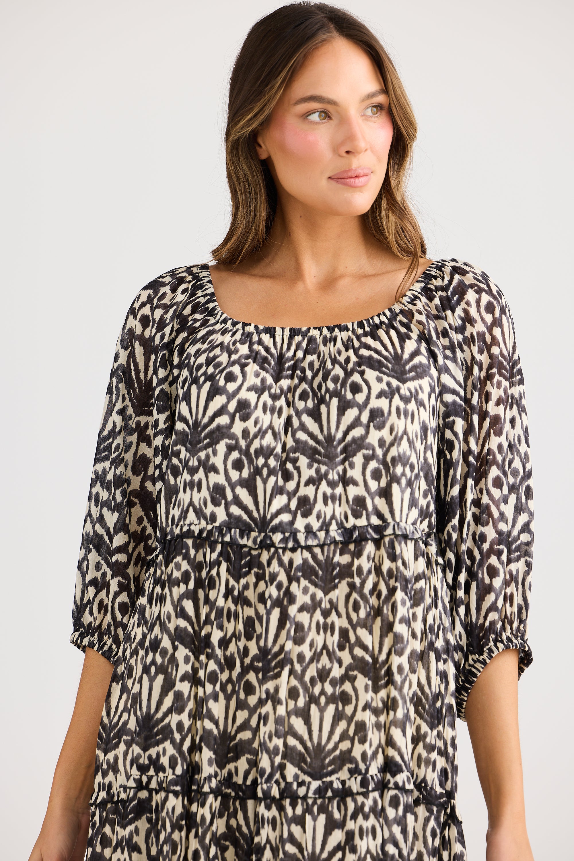 model wearing black cream long floral dress against white background