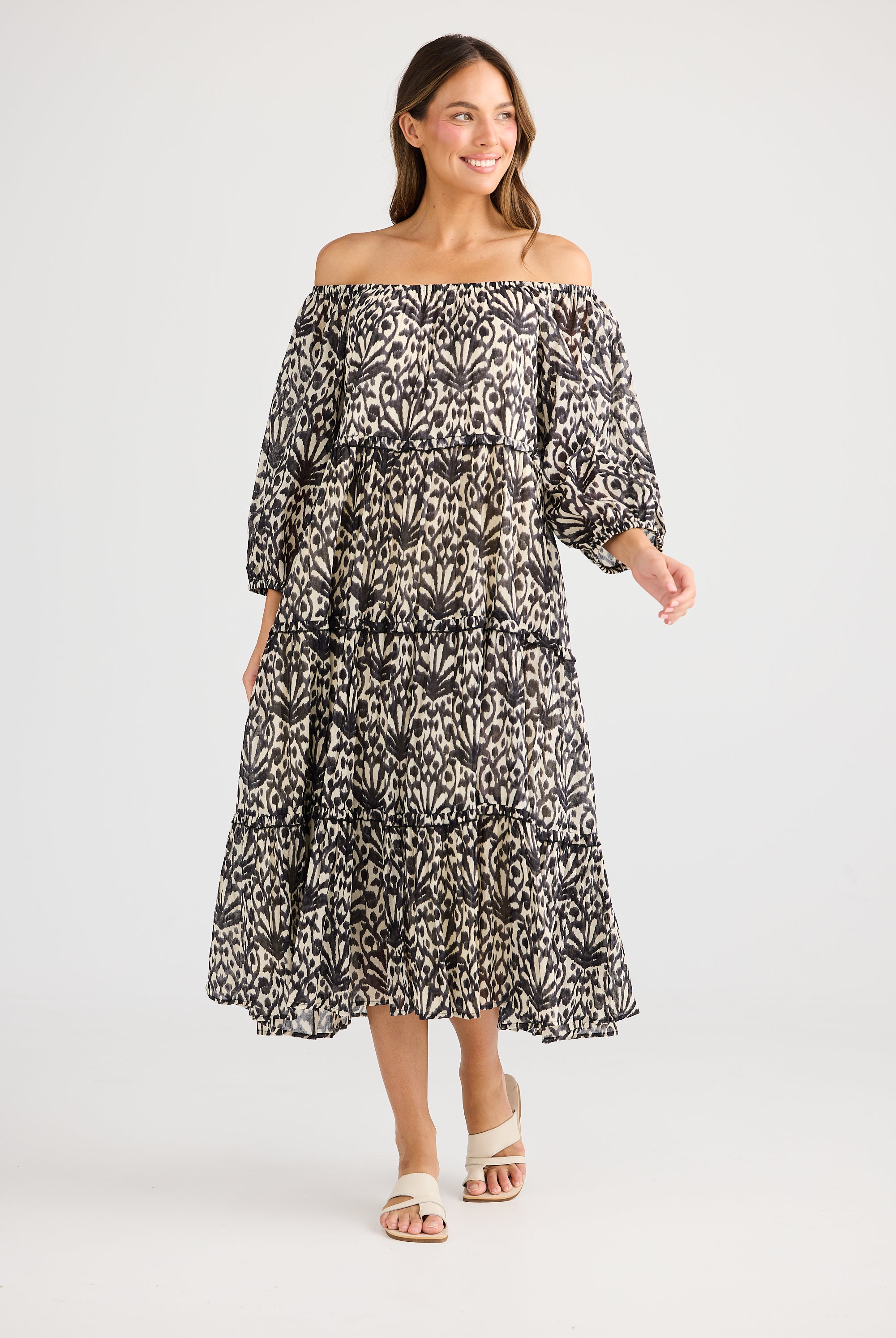 model wearing black cream long floral dress against white background