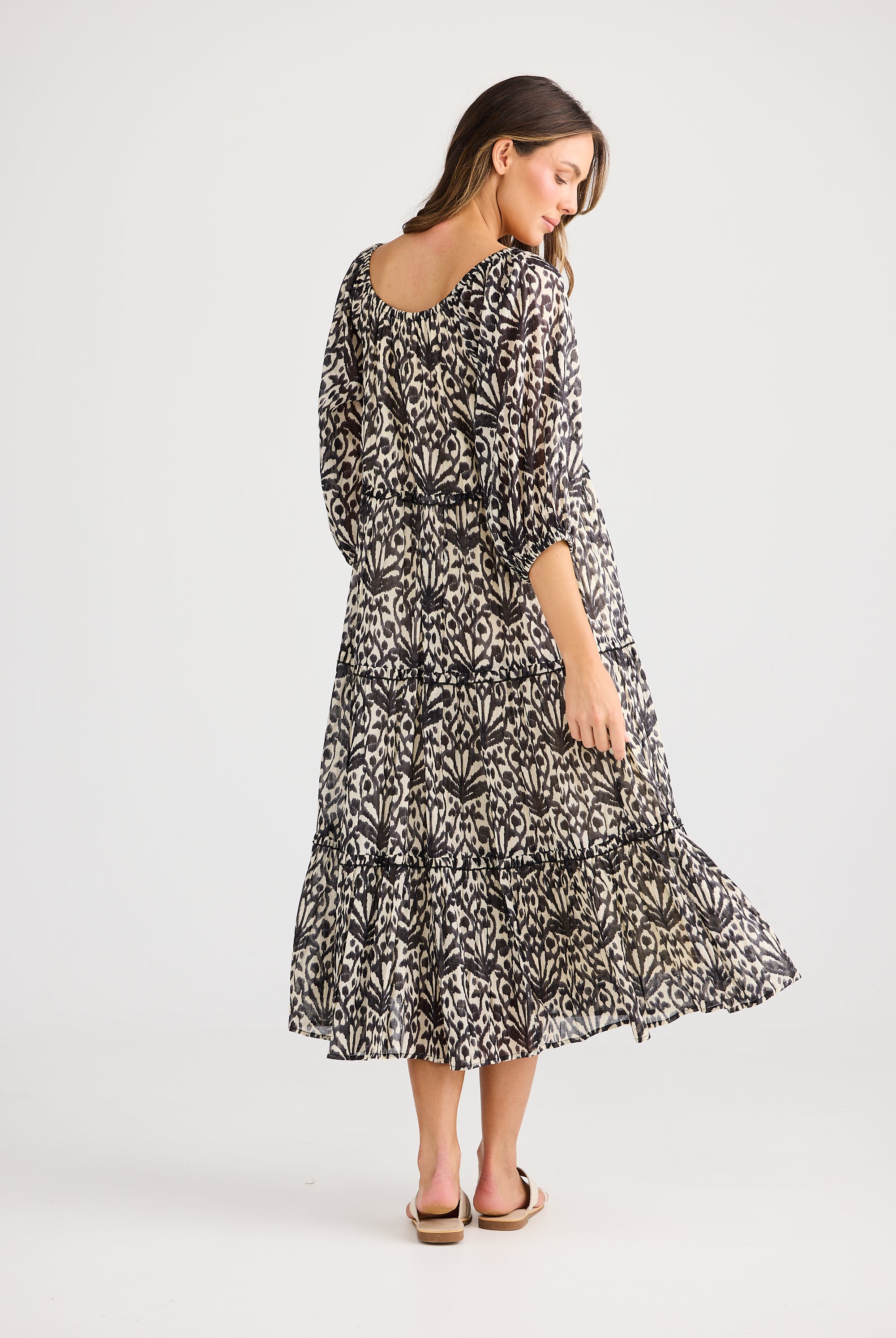 model wearing black cream long floral dress against white background back