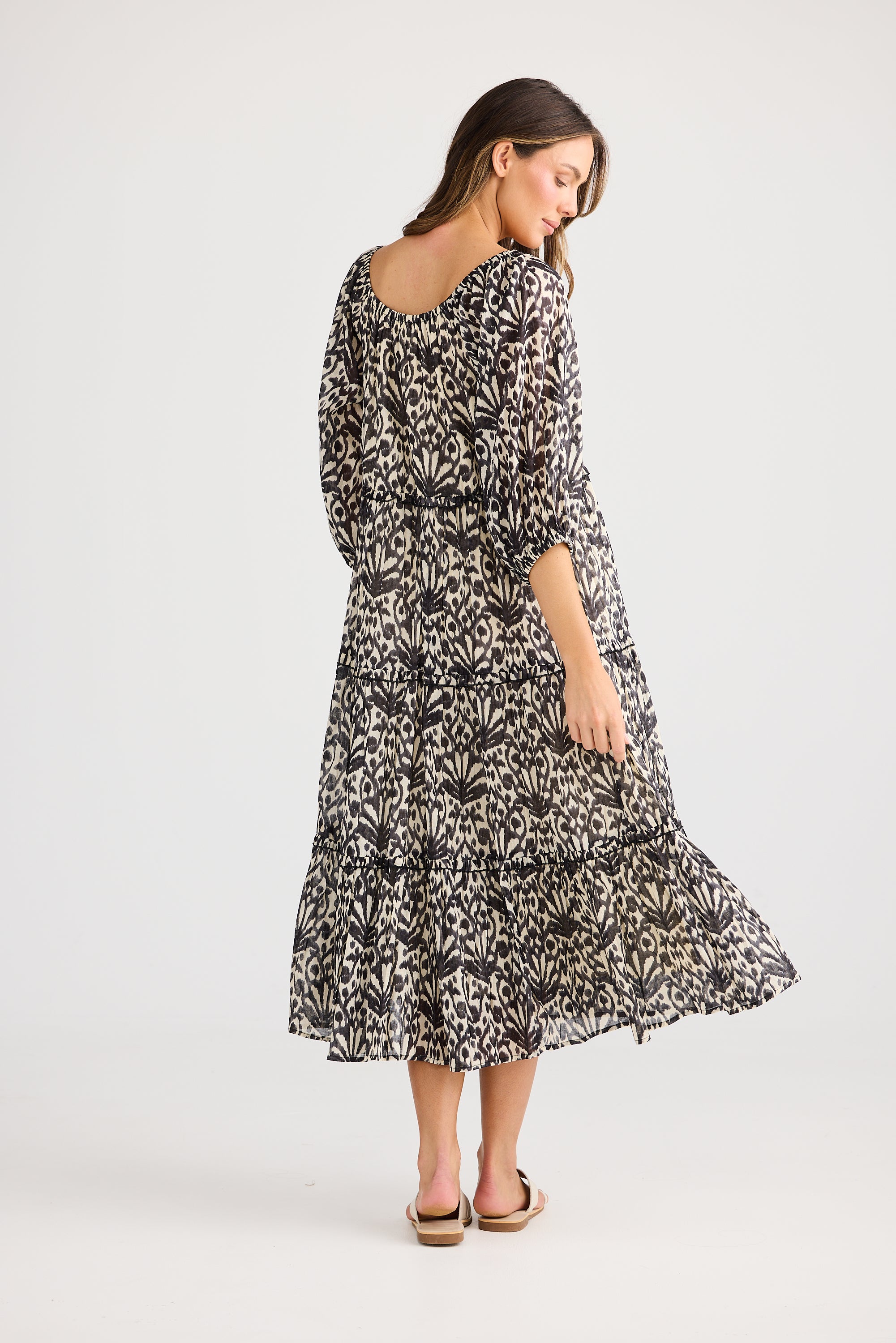 model wearing black cream long floral dress against white background back
