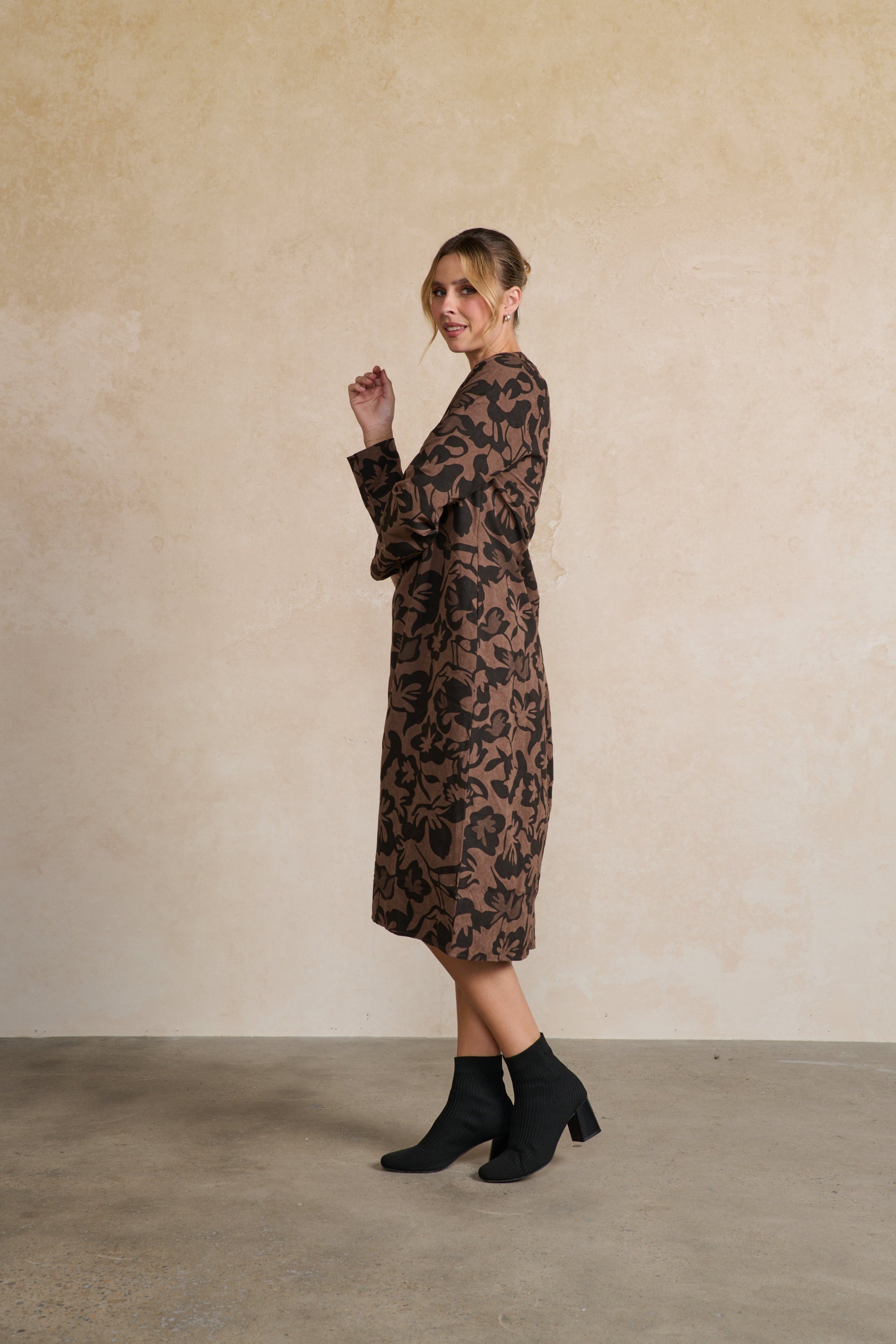Woman wearing a patterned dress against a plain background