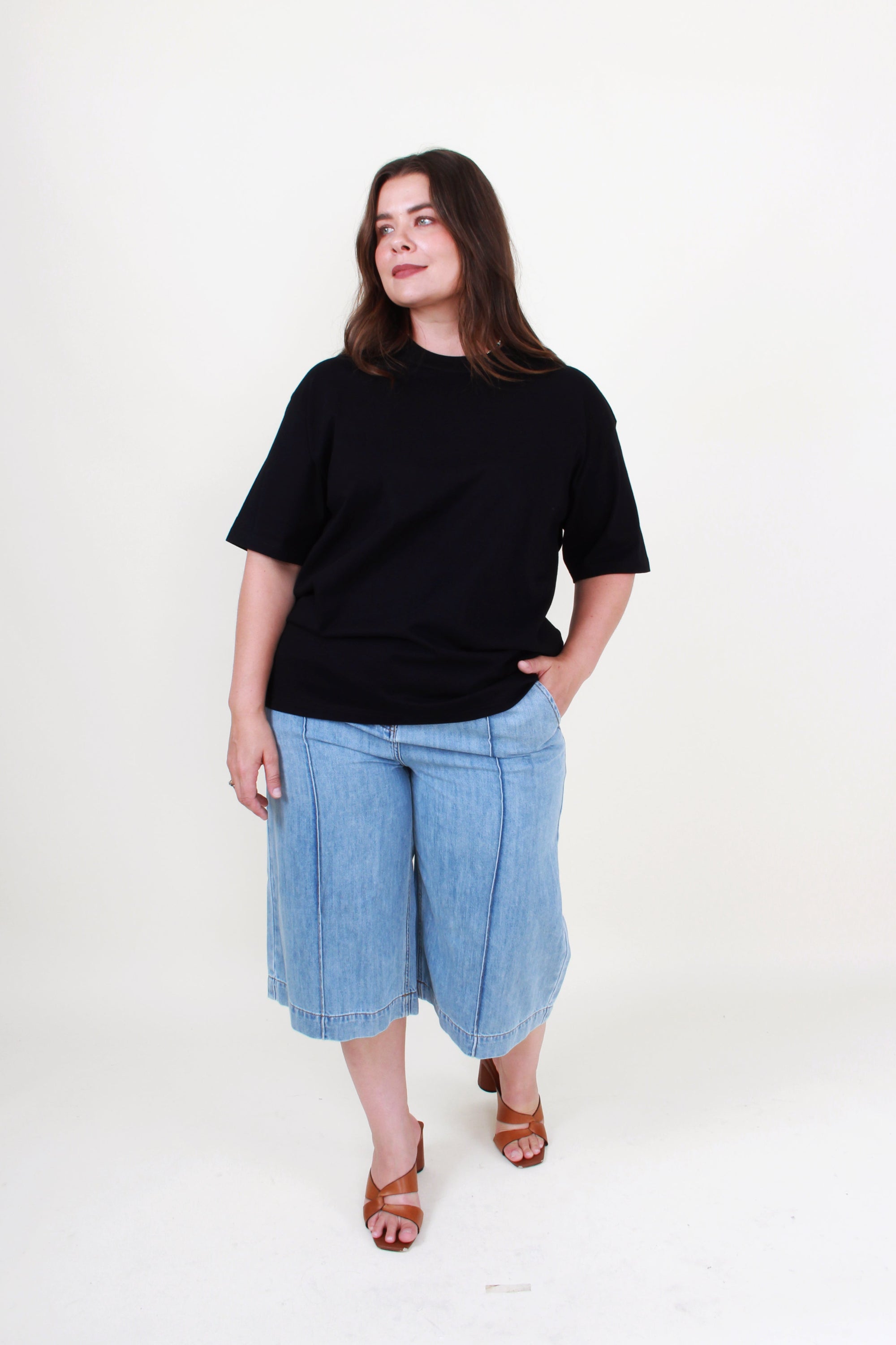 Woman wearing a black t-shirt and blue denim shorts on a white background