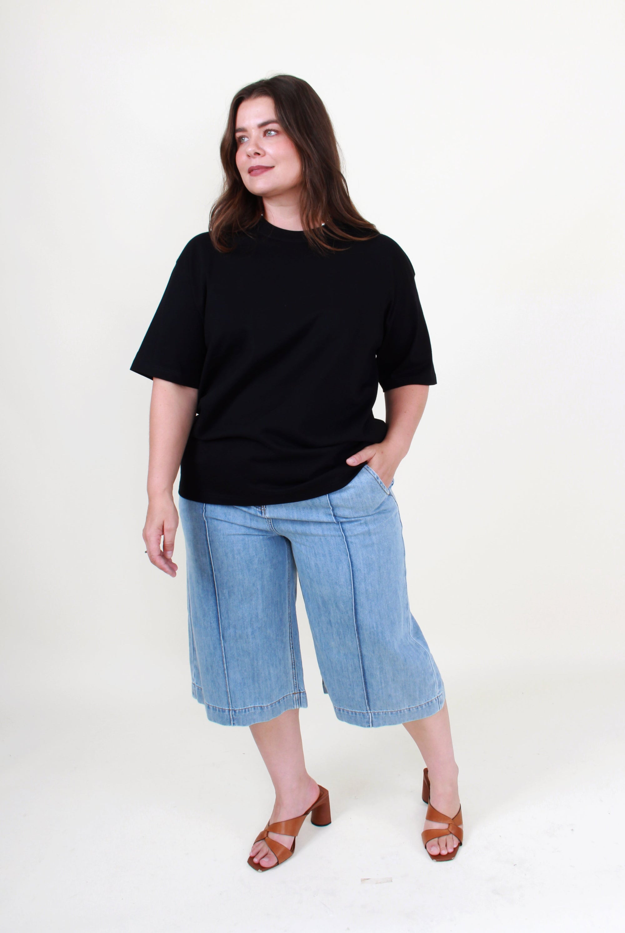 Woman wearing a black t-shirt and blue jeans on a white background