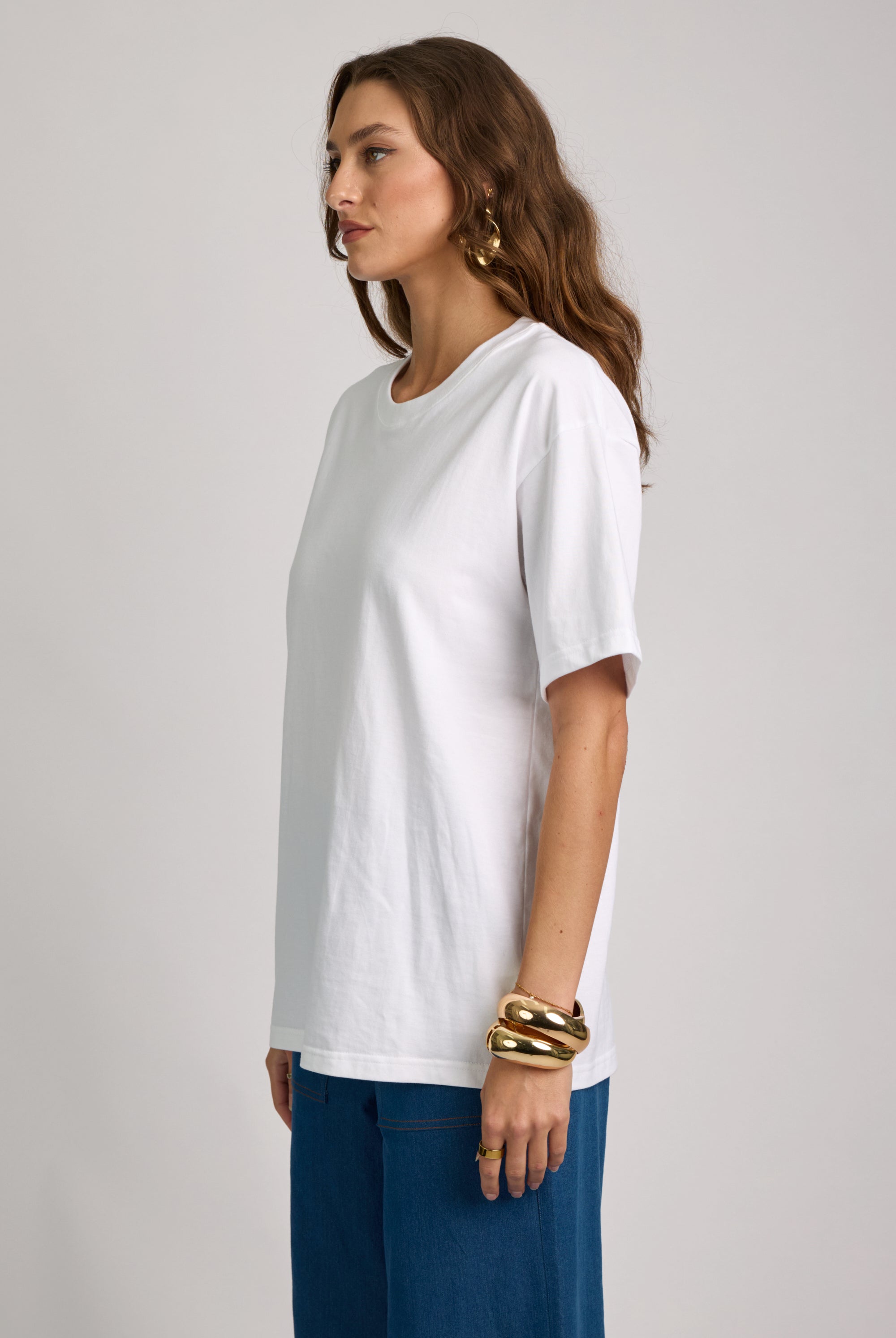 Woman wearing a white t-shirt and blue pants on a plain background