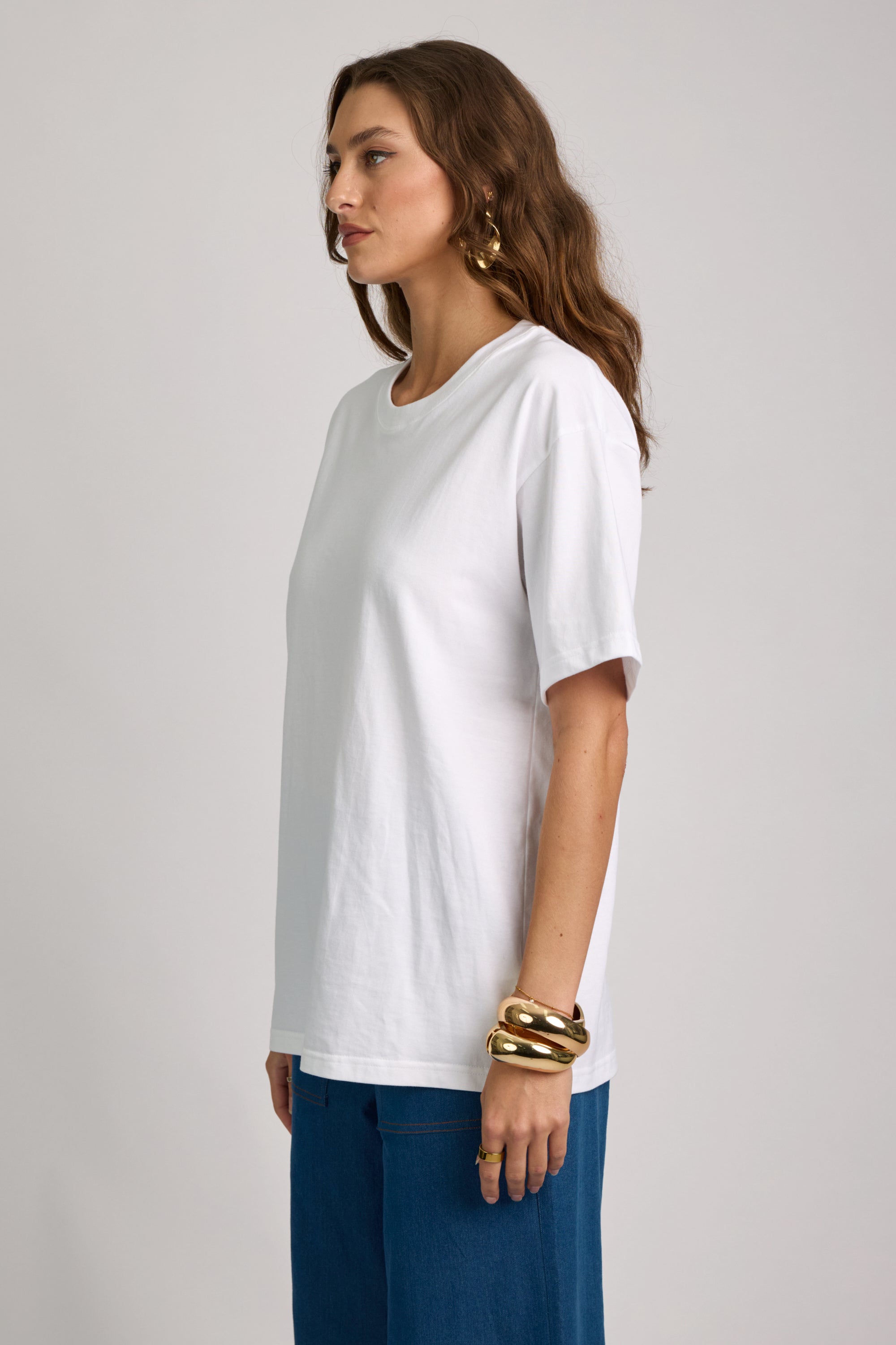 Woman wearing a white t-shirt and blue pants on a plain background