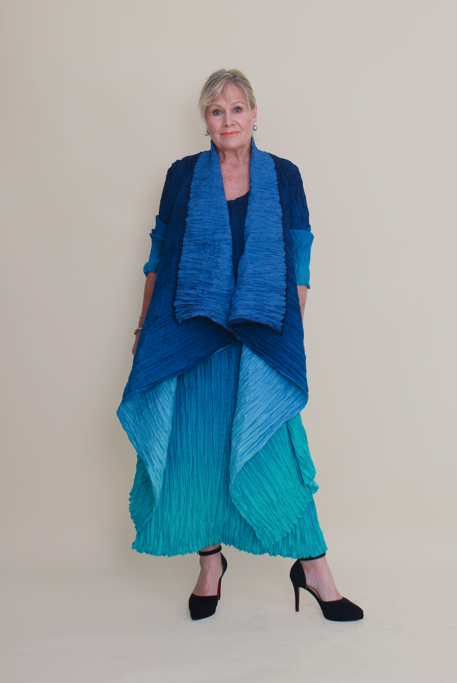 Woman wearing a blue and green outfit against a plain background