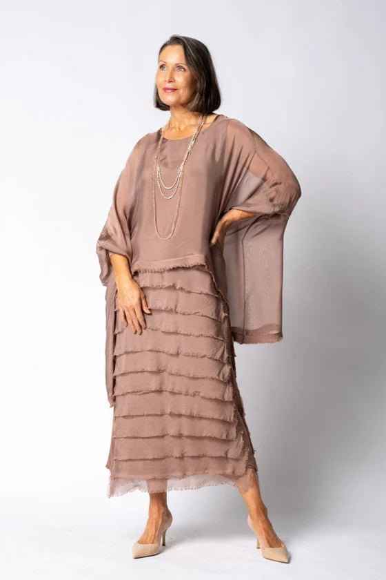 Woman wearing a brown layered dress with a plain background