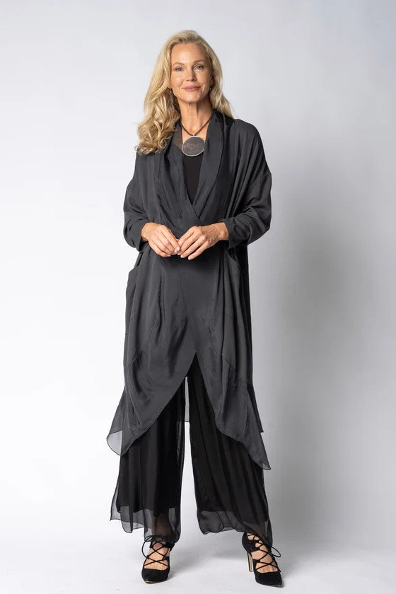 Woman wearing longline dark grey top over black dress on light grey background