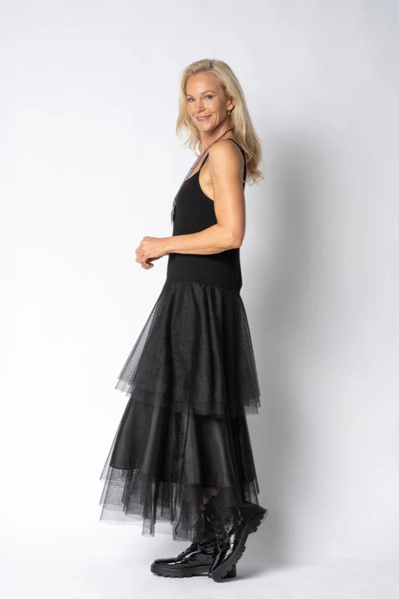 Woman wearing a black dress with a sheer overlay on a white background side angle