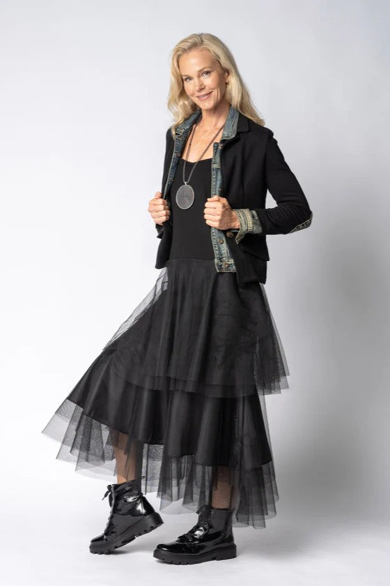 Woman wearing a black dress with sheer overlay and black jacket on a white background