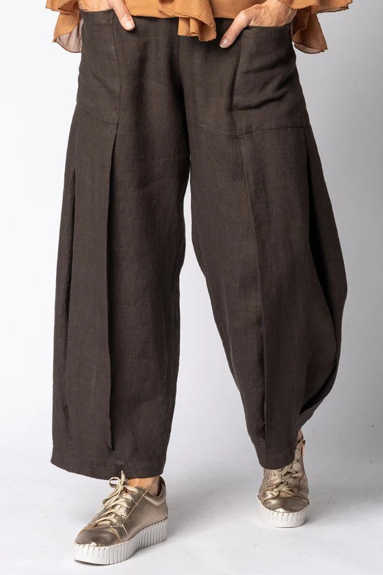 Brown wide-leg pants worn with a light brown top and sneakers on a white background