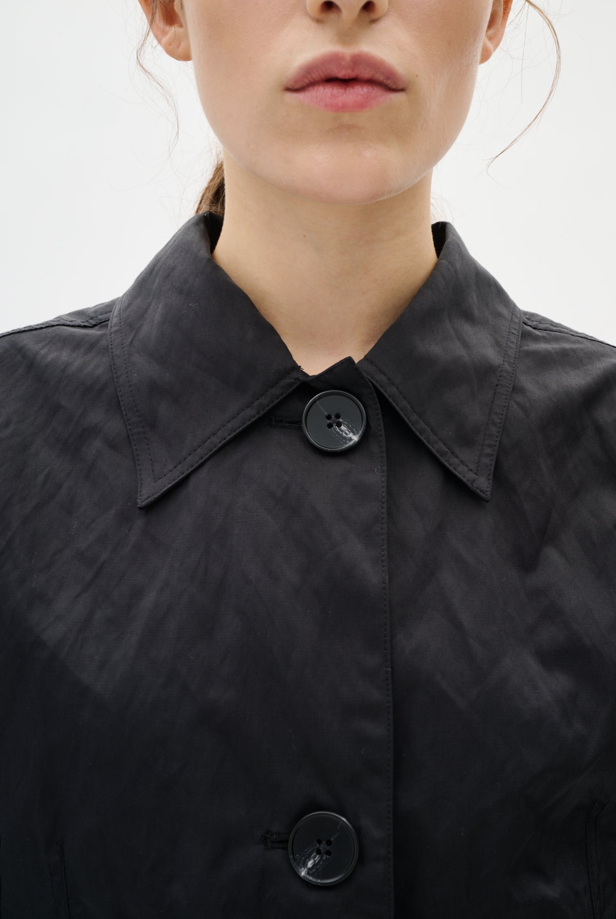 Close-up of a black jacket with buttons on a white background