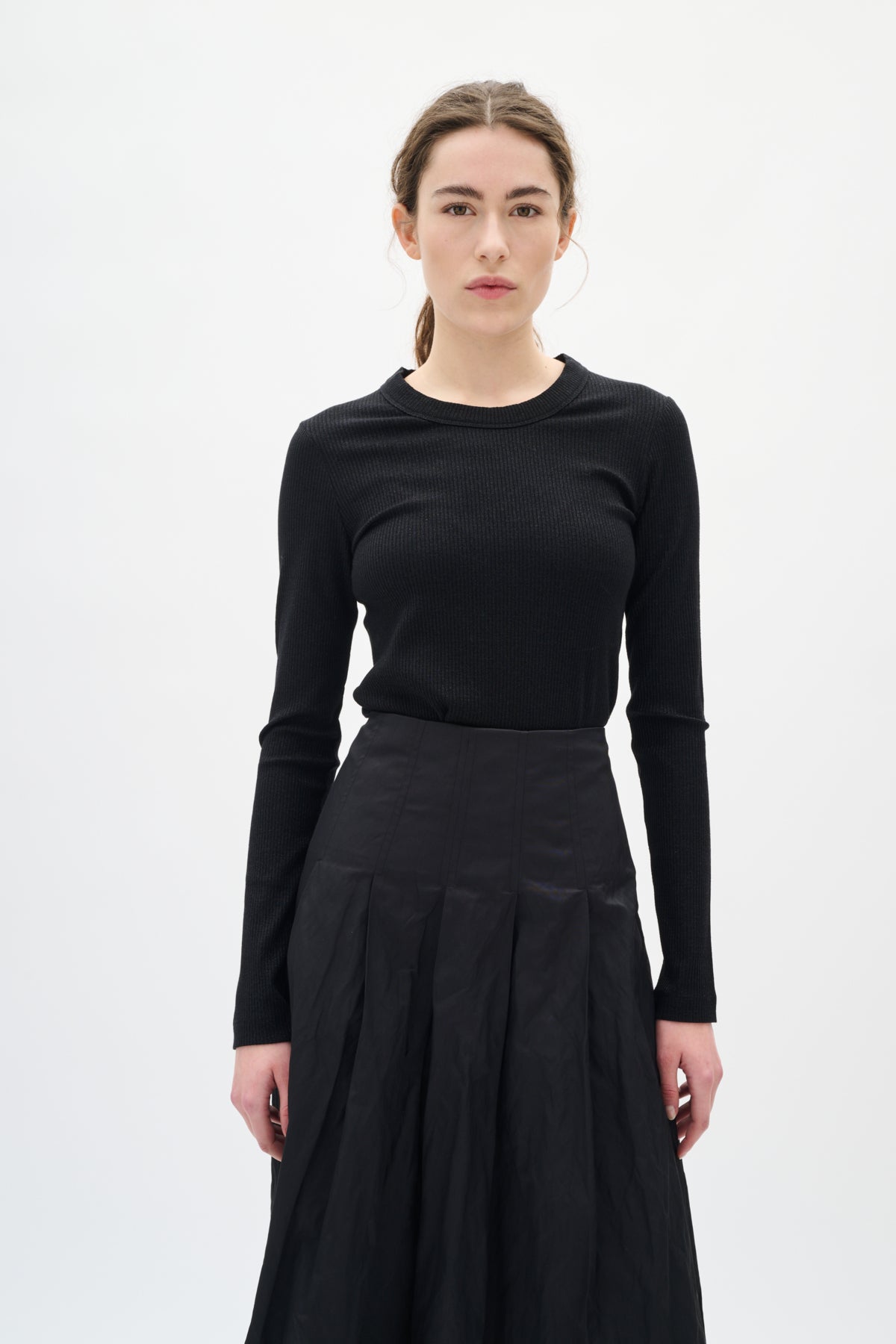 Woman wearing a black long-sleeve top and black skirt on a white background