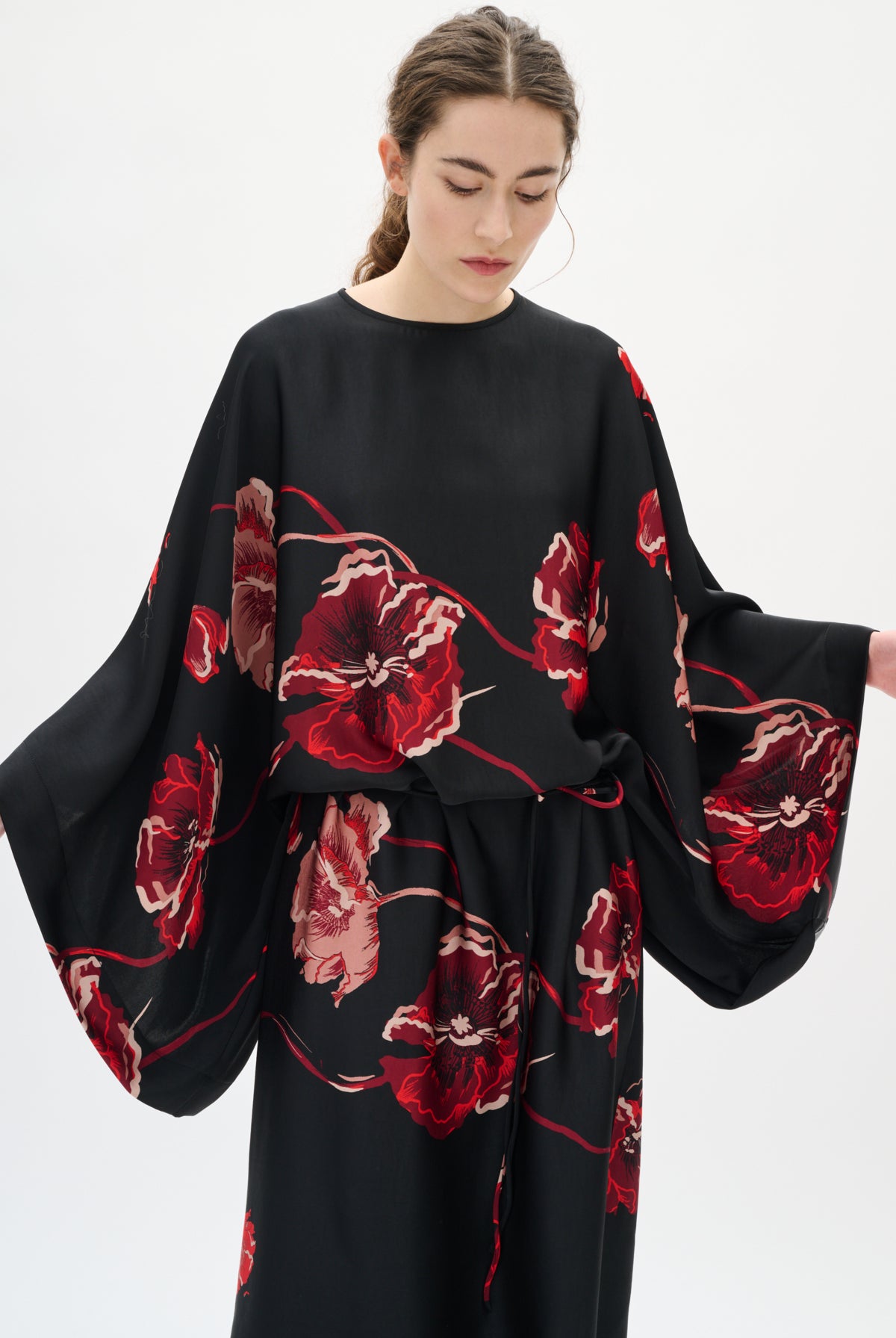 Woman wearing a black dress with red floral patterns on a white background