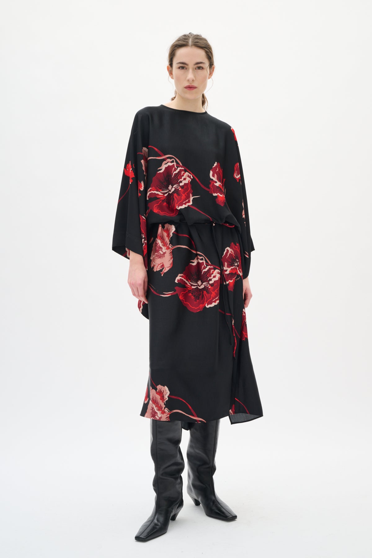 Woman wearing a black dress with red floral patterns on a white background