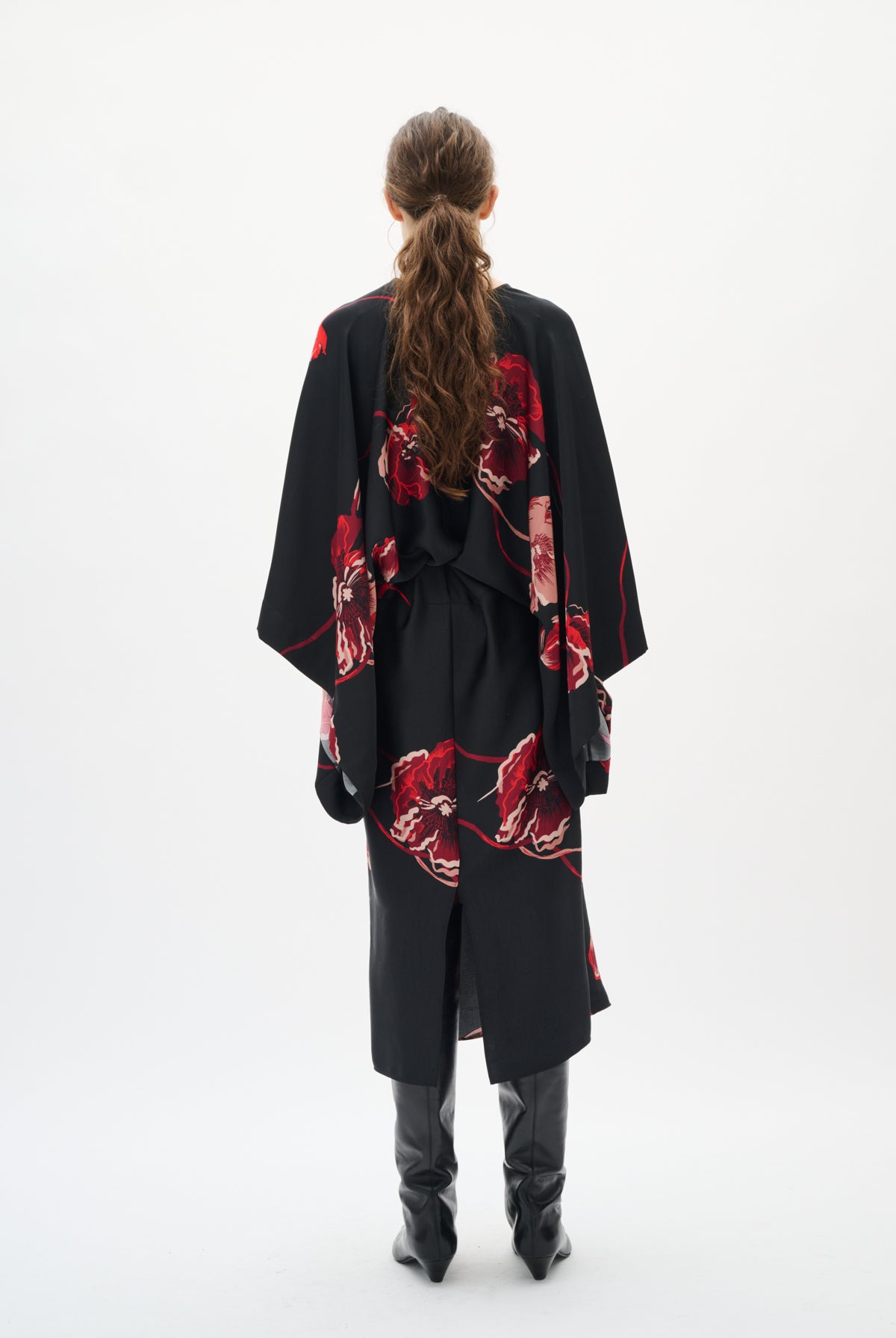 Person wearing a black dresswith red floral patterns from behind on a white background back angle