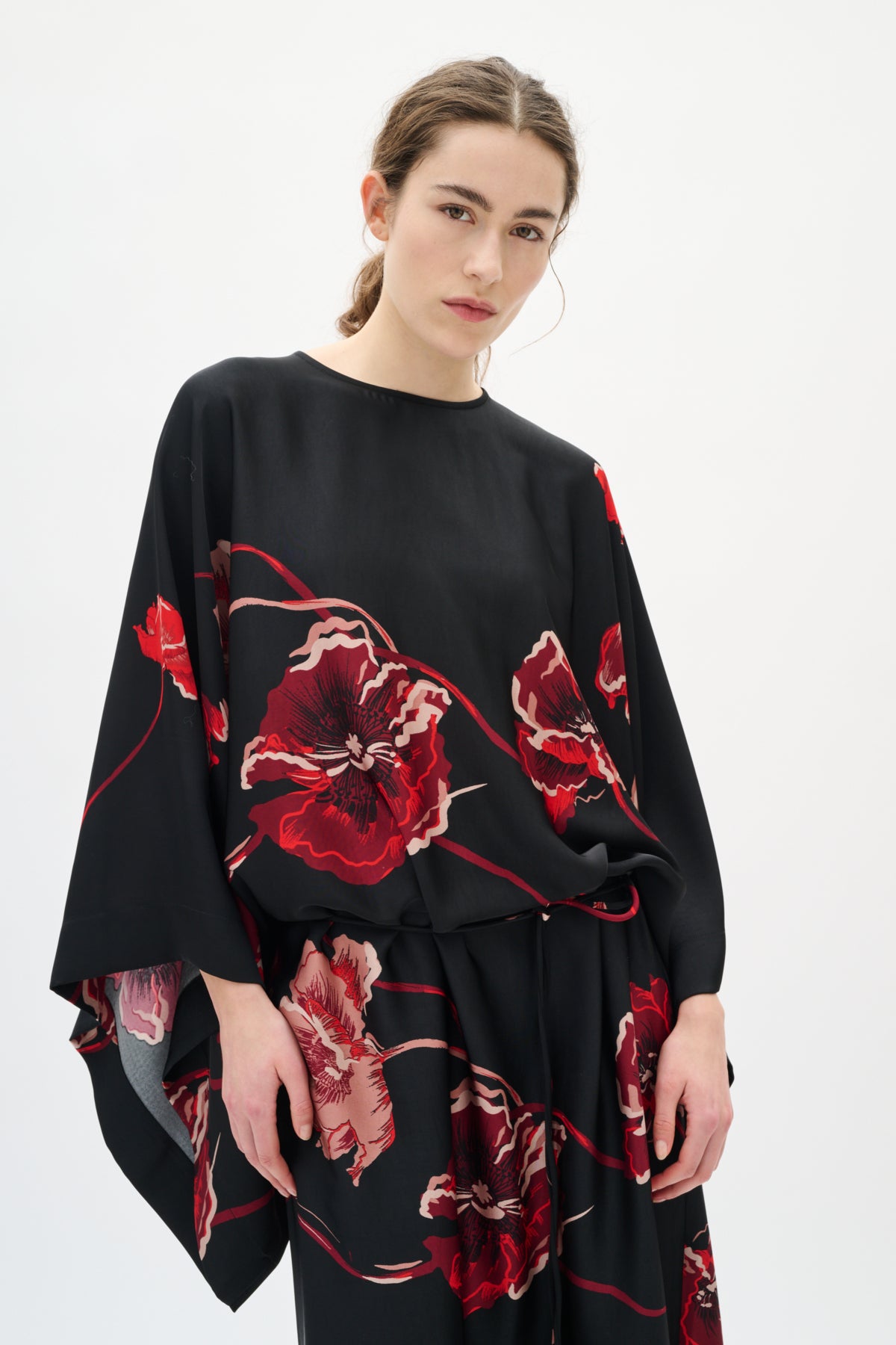 Woman wearing a black dress with red floral patterns on a white background