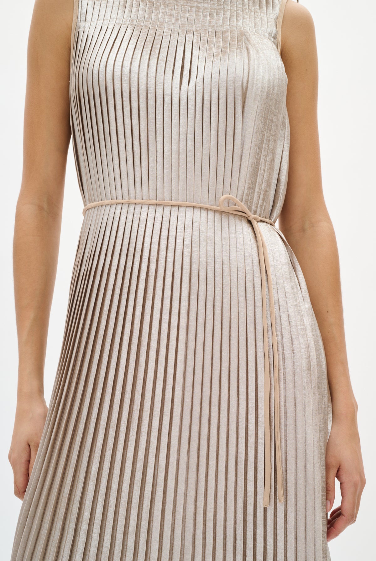 Woman wearing a silver beige pleated dress on a white background close up