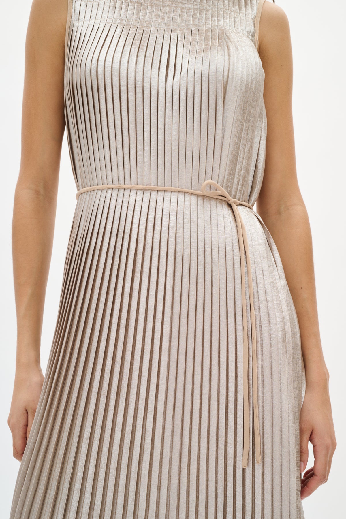 Woman wearing a silver beige pleated dress on a white background close up