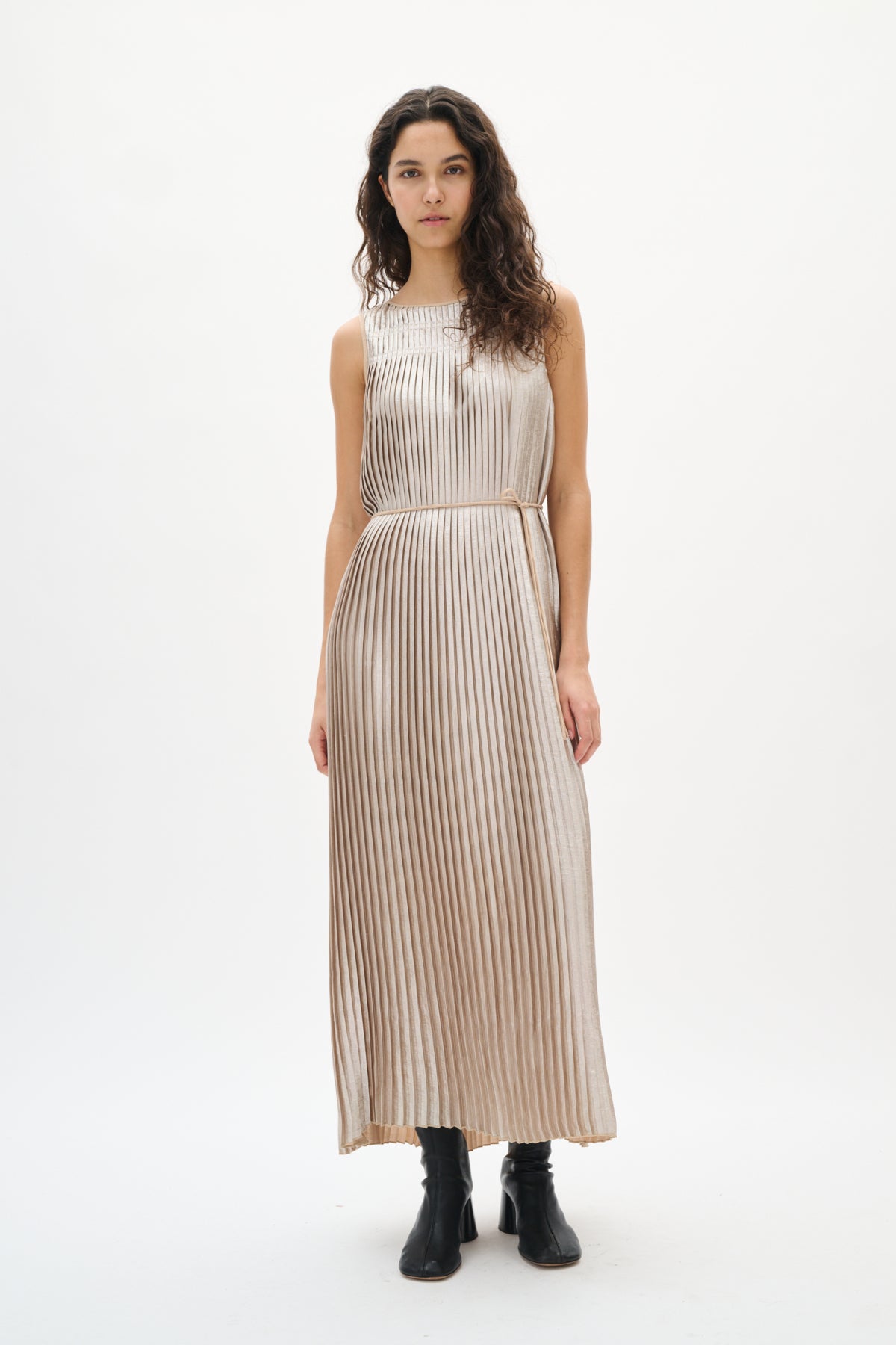 Woman wearing a silver beige pleated dress on a white background