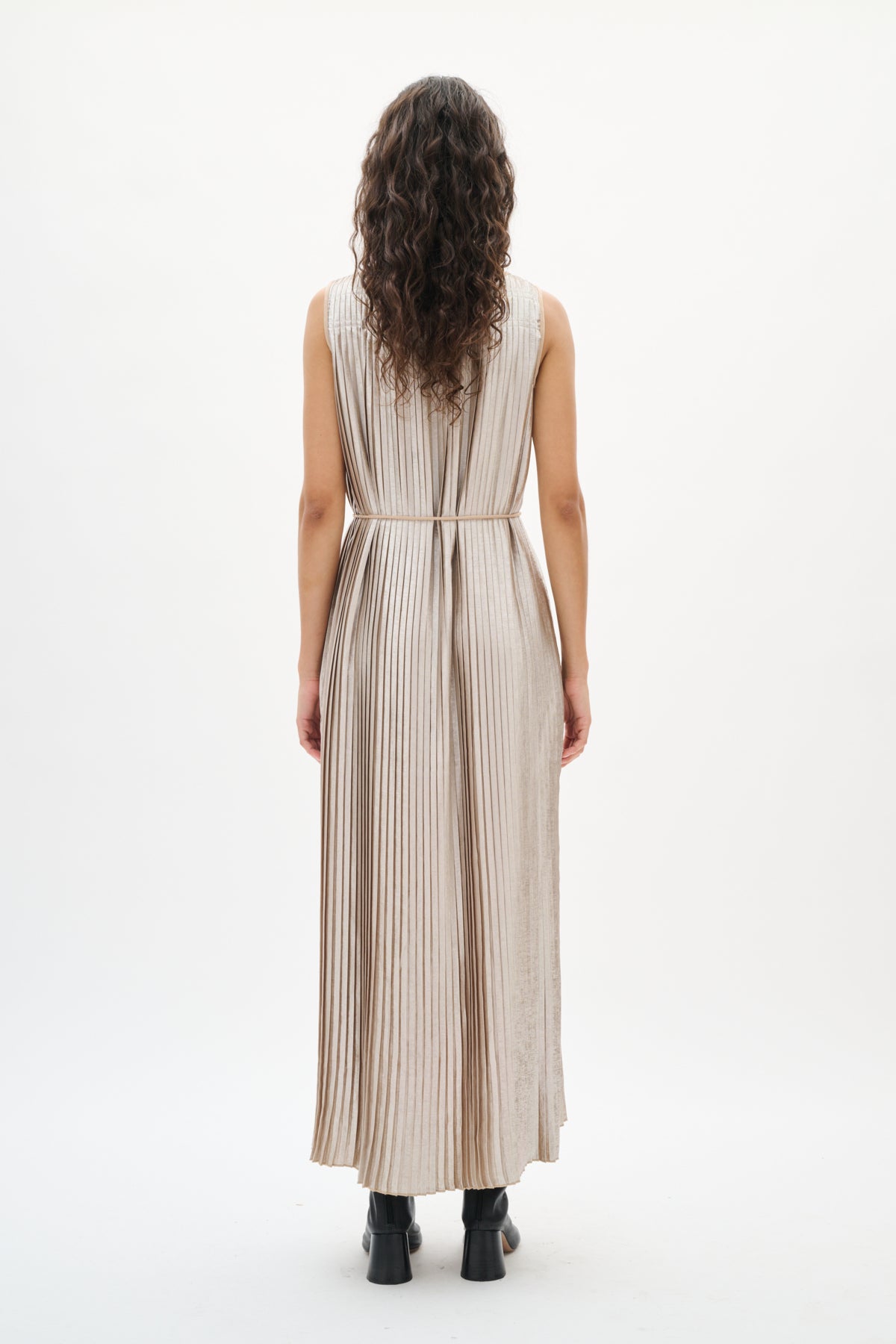 Woman wearing a silver beige pleated dress on a white background back angle