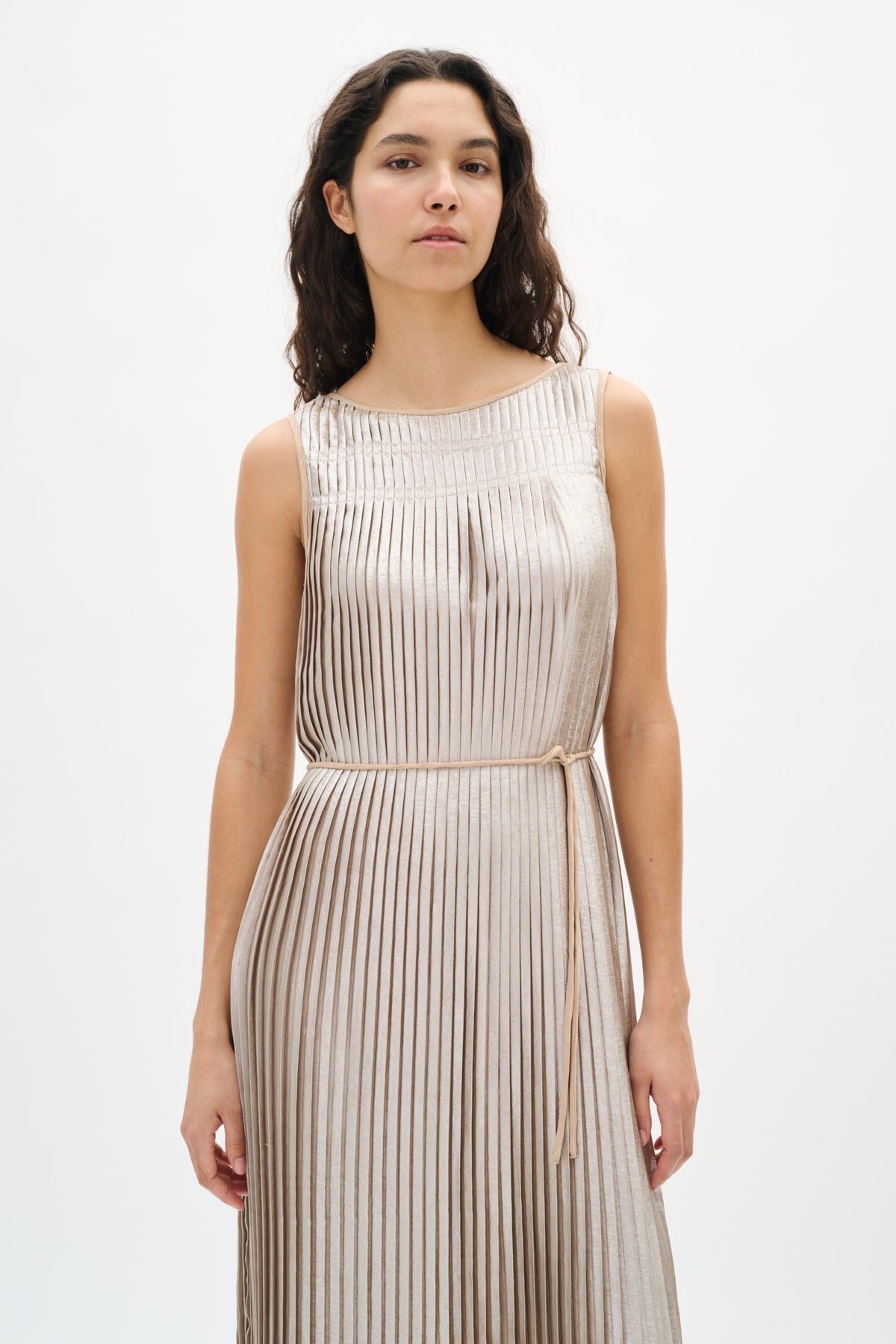 Woman wearing a silver beige pleated dress on a white background