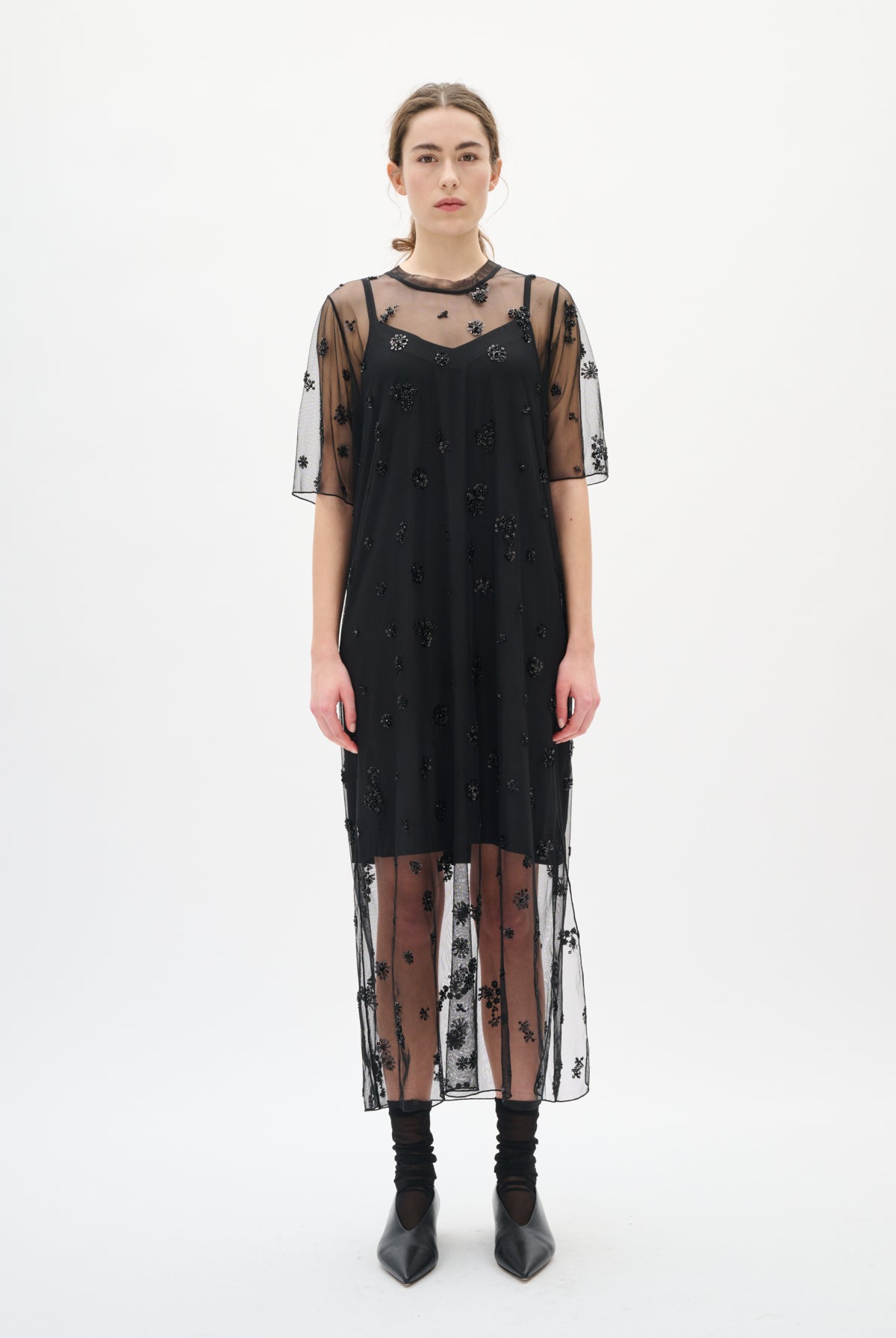 Black dress with sheer sleeves and bottom half on a white background