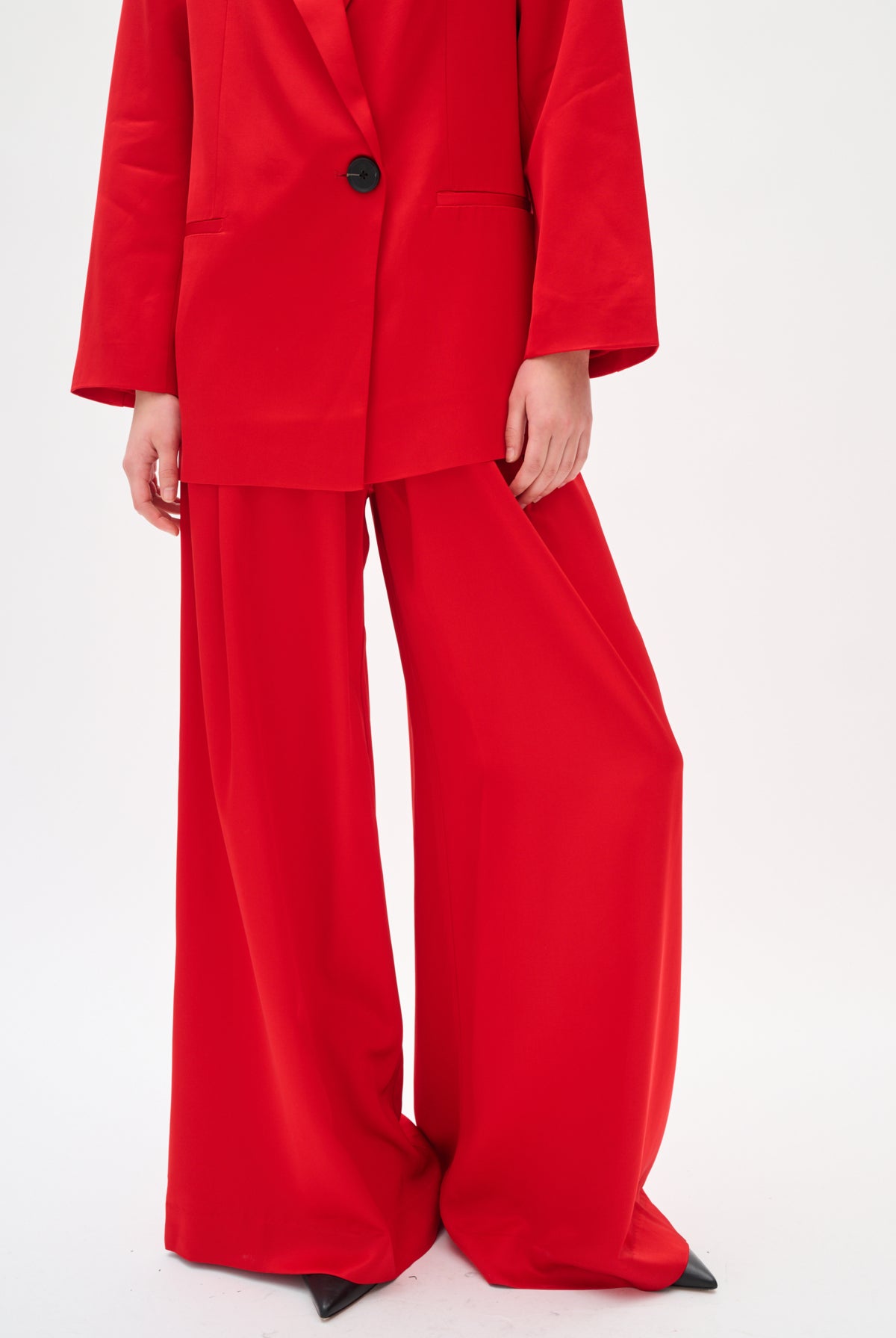Person wearing a red suit with wide-leg pants on a white background
