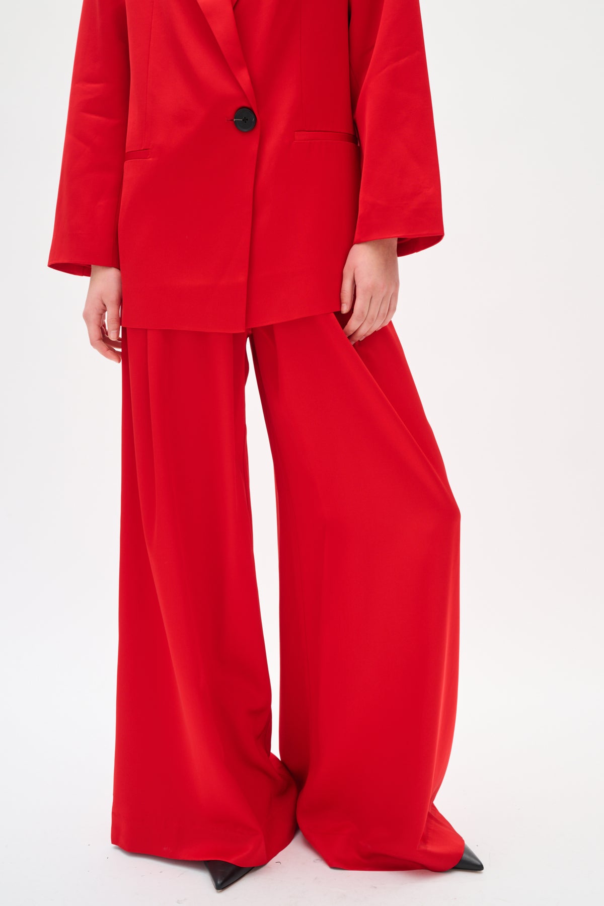 Person wearing a red suit with wide-leg pants on a white background
