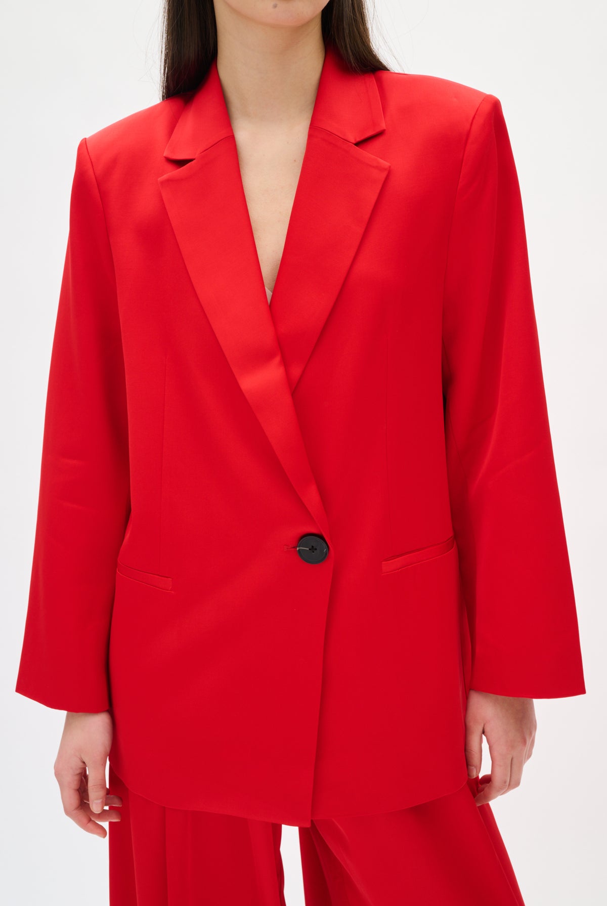 Red suit jacket with a black button on a white background