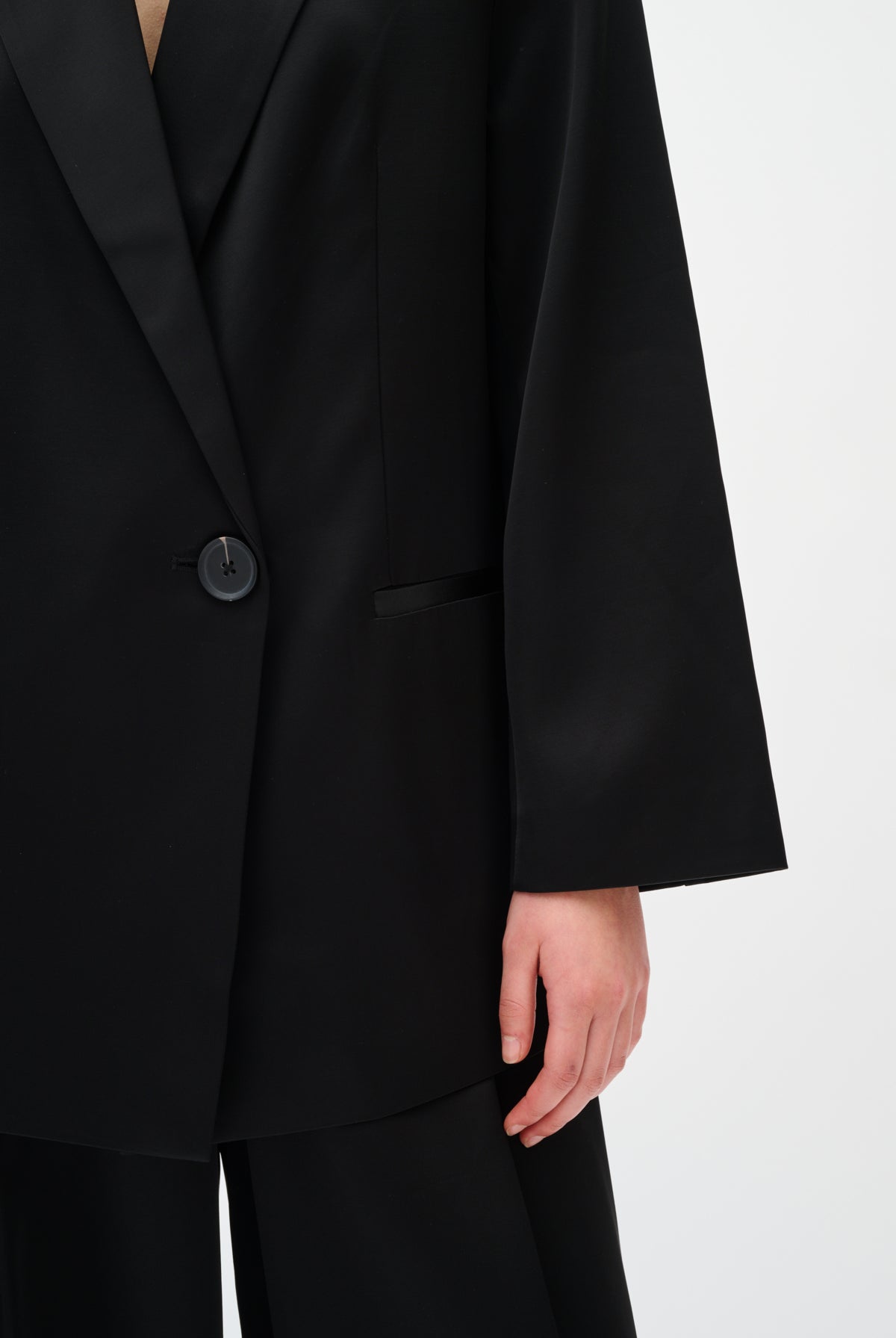 Black suit jacket worn by a person on a white background