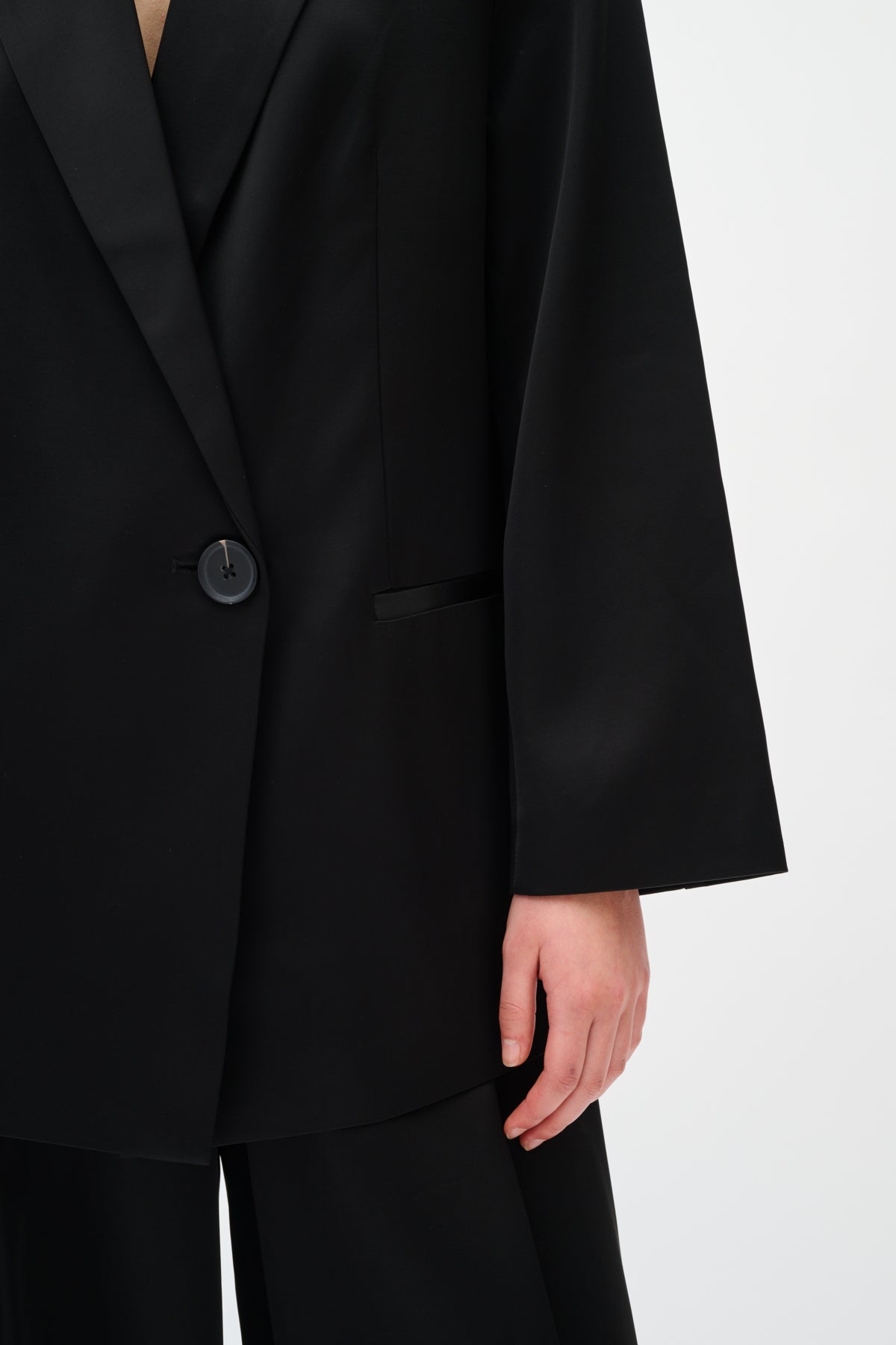 Black suit jacket worn by a person on a white background