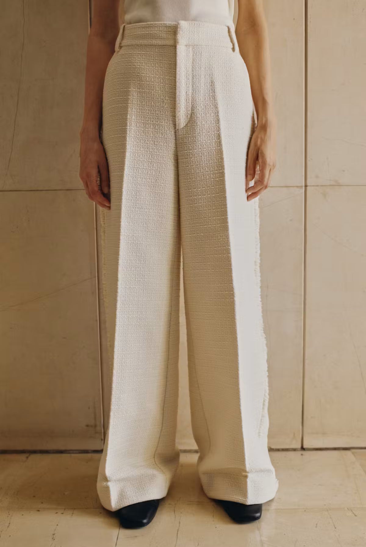 Person wearing beige and white pants against a neutral background