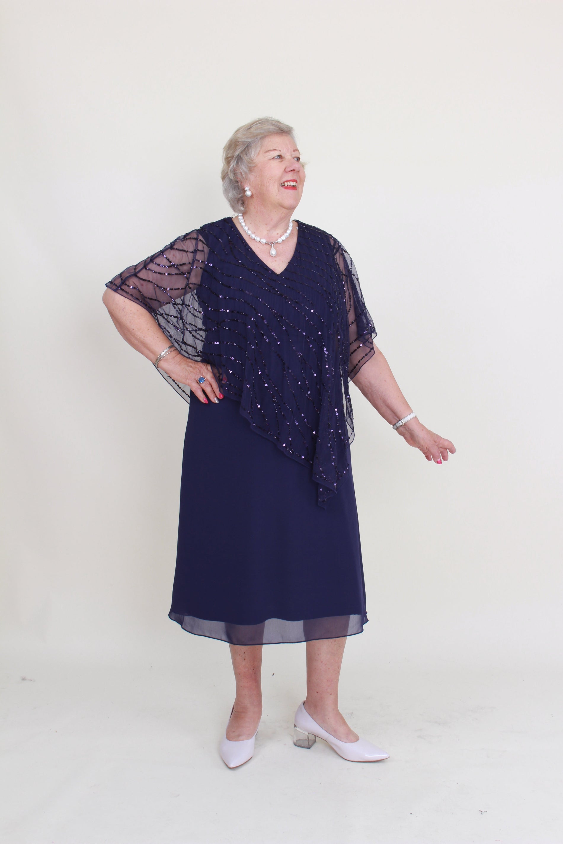 Woman wearing a dark blue dress with beaded details on a white background